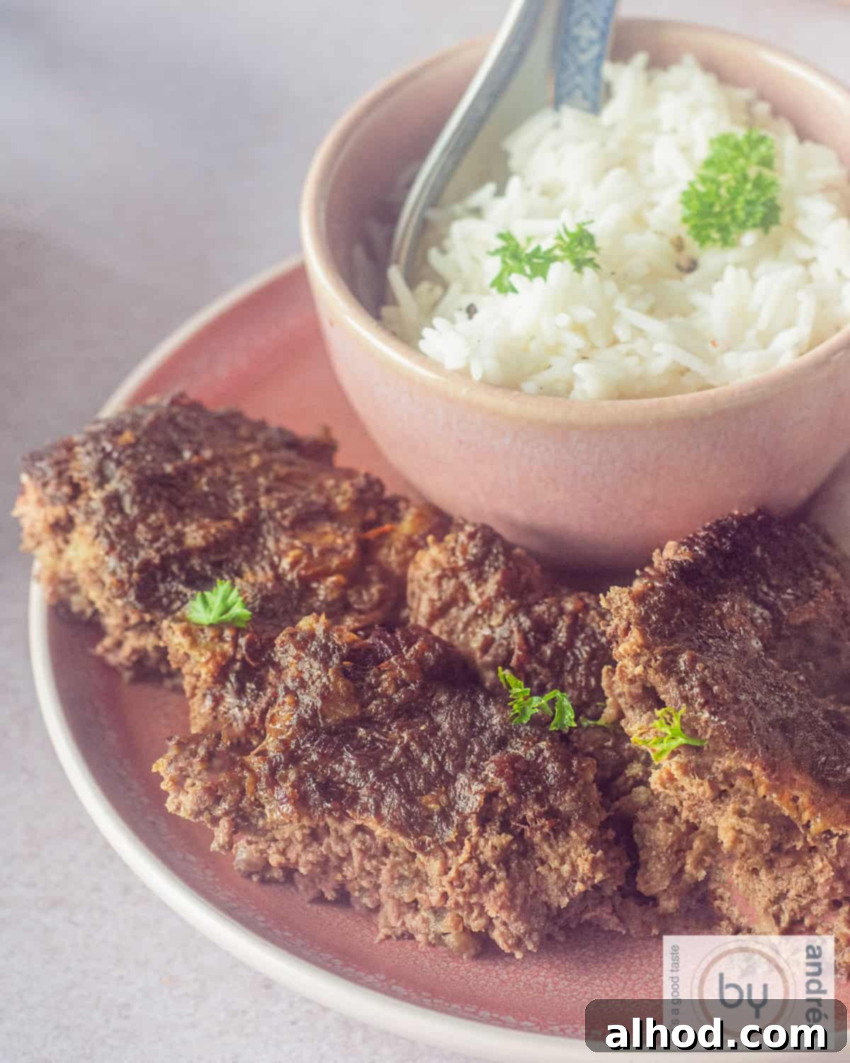 A close-up shot of a plate with several golden-brown pieces of Indonesian Frikadel Pan, accompanied by a small bowl of steamed white rice, highlighting the texture and inviting presentation of the dish.