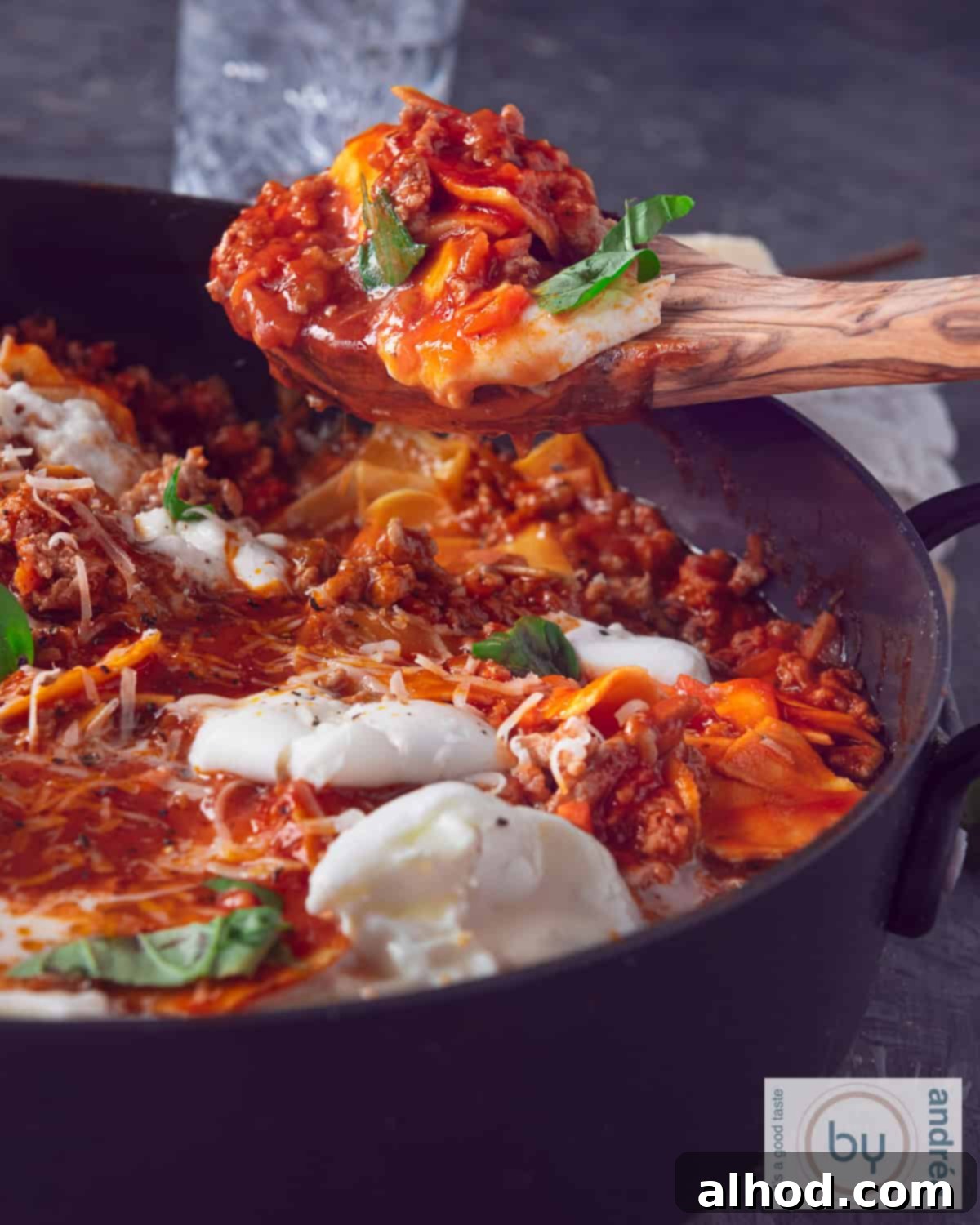 A black casserole pan filled with freshly made, saucy lasagnette with melted cheese, ready to be served.