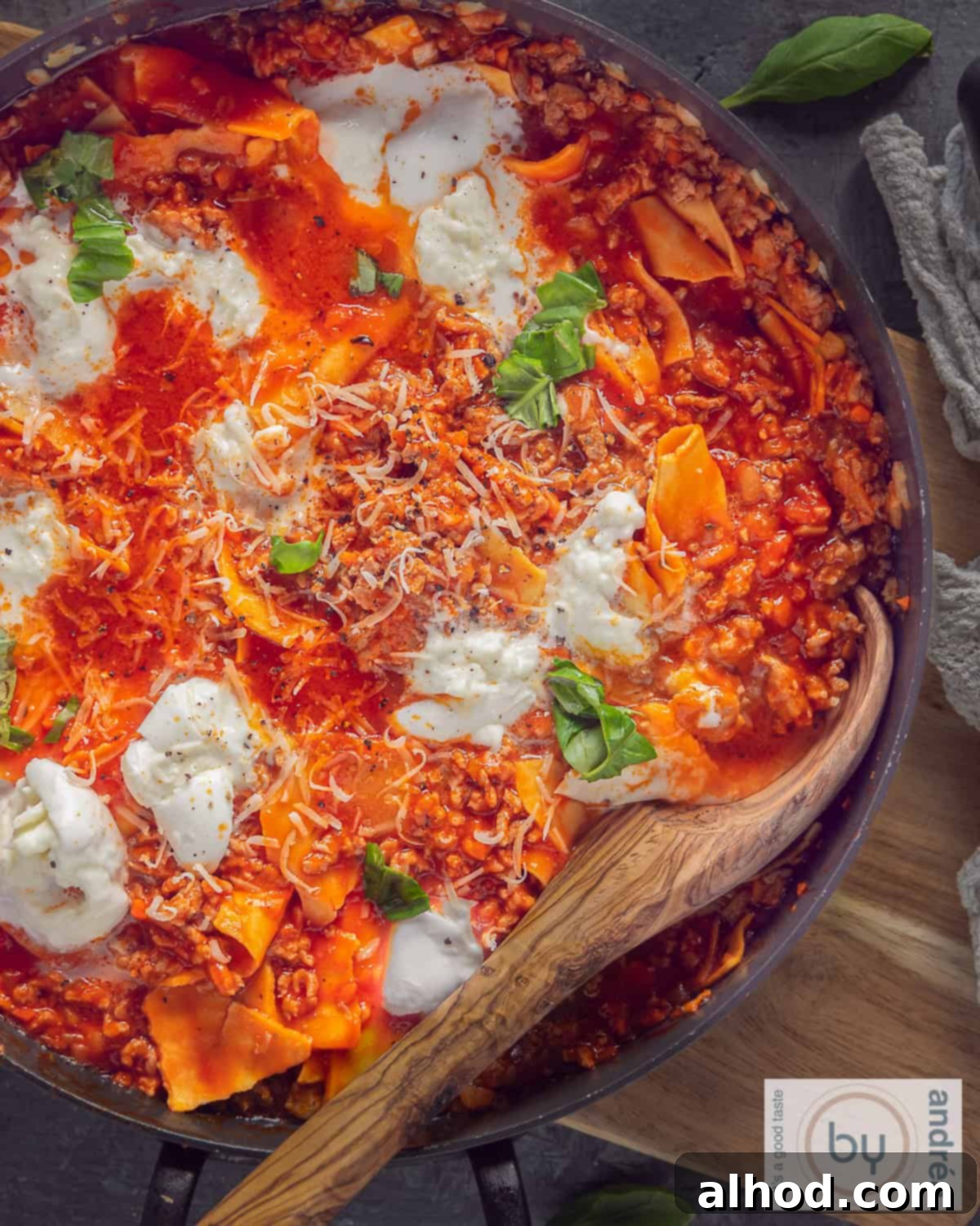 Effortless 20-Minute Skillet Lasagna 3 A top-down view of a large skillet filled with bubbling skillet lasagna, a wooden spoon resting in the rich, cheesy dish.