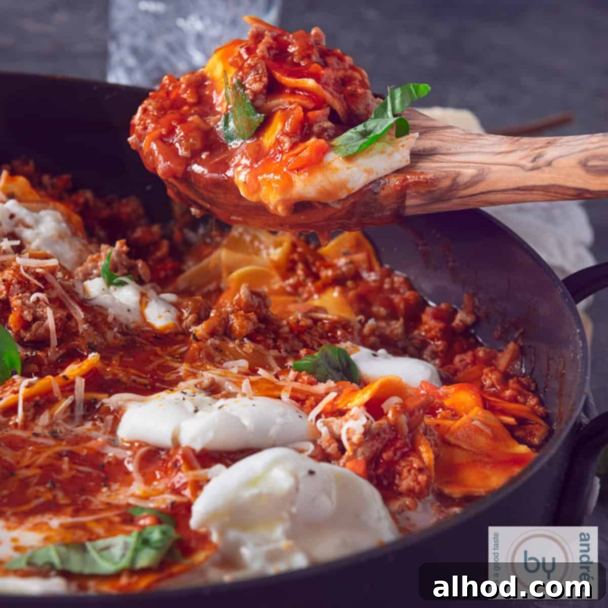 Effortless 20-Minute Skillet Lasagna 4 A square photo of a skillet with lasagnette. A wooden spoon holds up some lasagnette, showing the rich sauce and melted cheese.