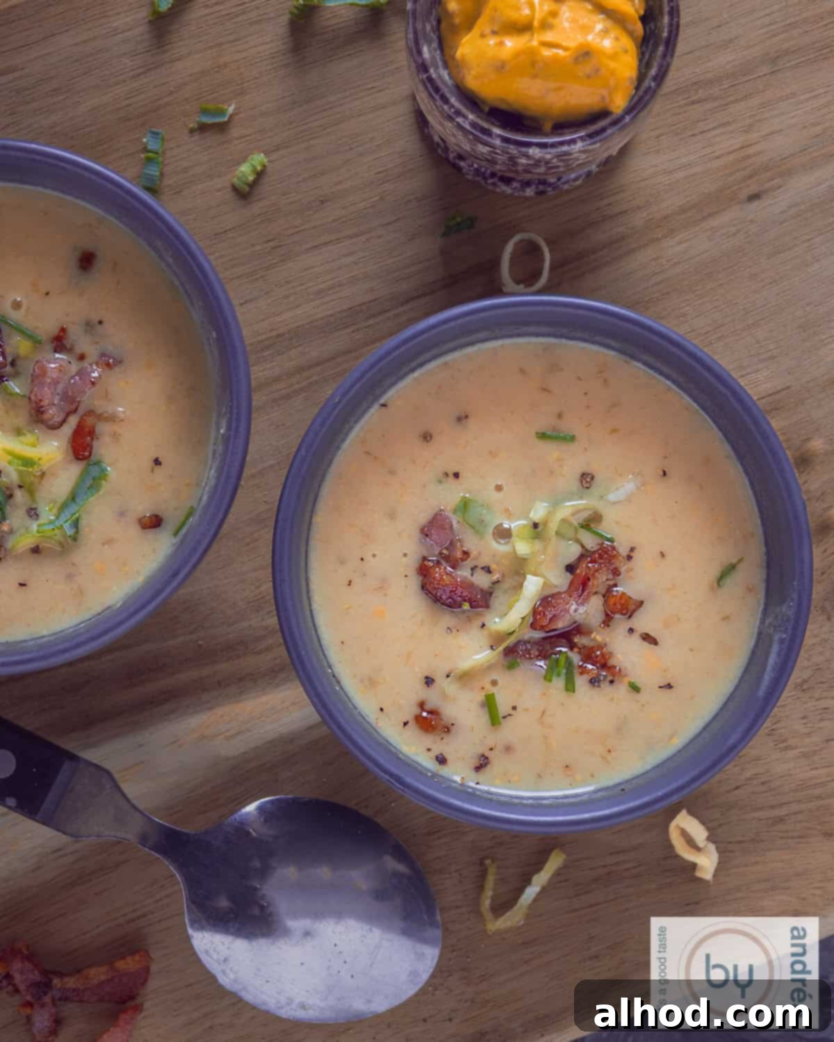 Hearty Groninger Mustard Soup with Bacon and Leek 3 A photo from above of two bowls of Groningen Mustard Soup with crispy bacon and fresh leek on a wooden board.