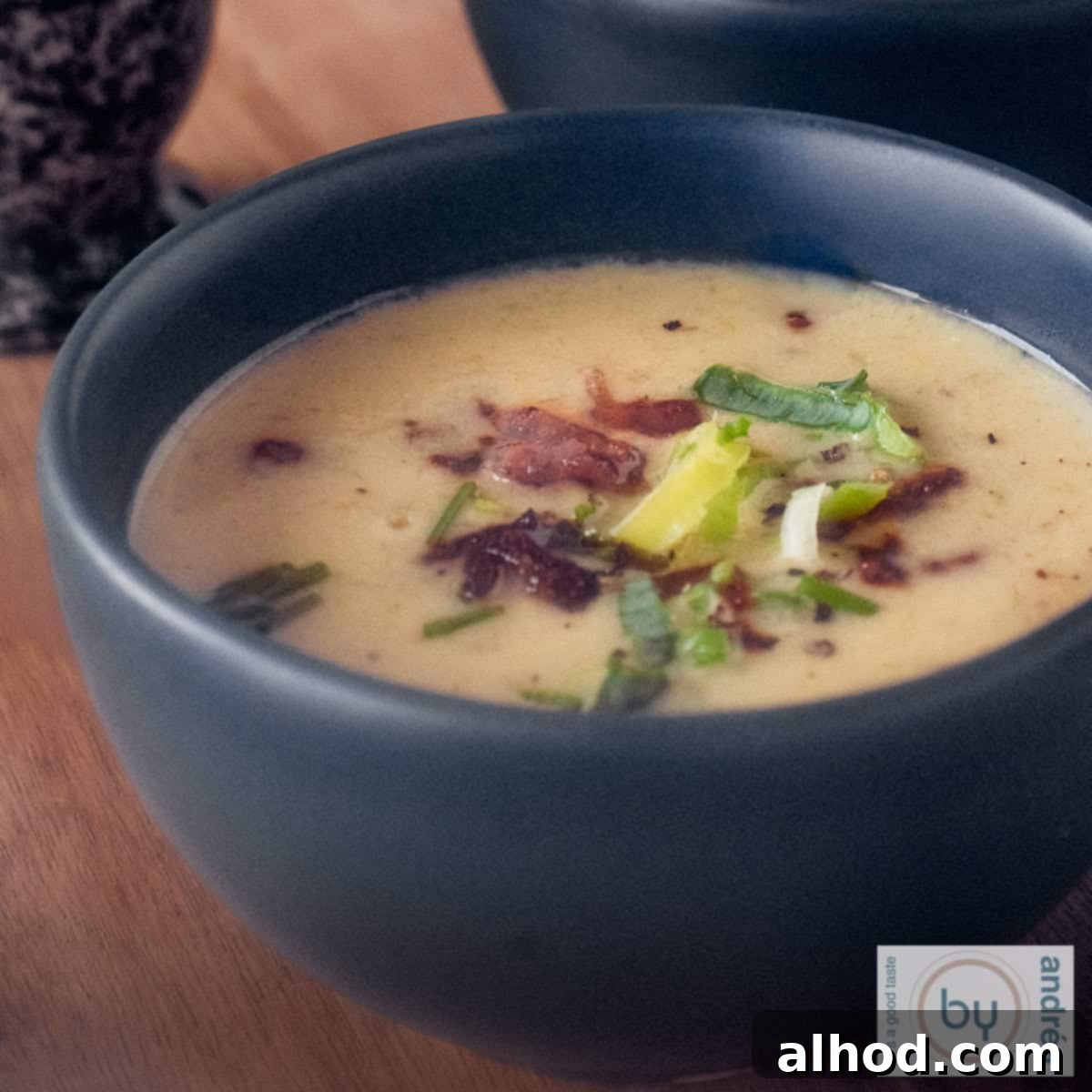 Hearty Groninger Mustard Soup with Bacon and Leek 4 A square photo of a dark gray bowl of Groningen mustard soup with leek and bacon, ready to be served.