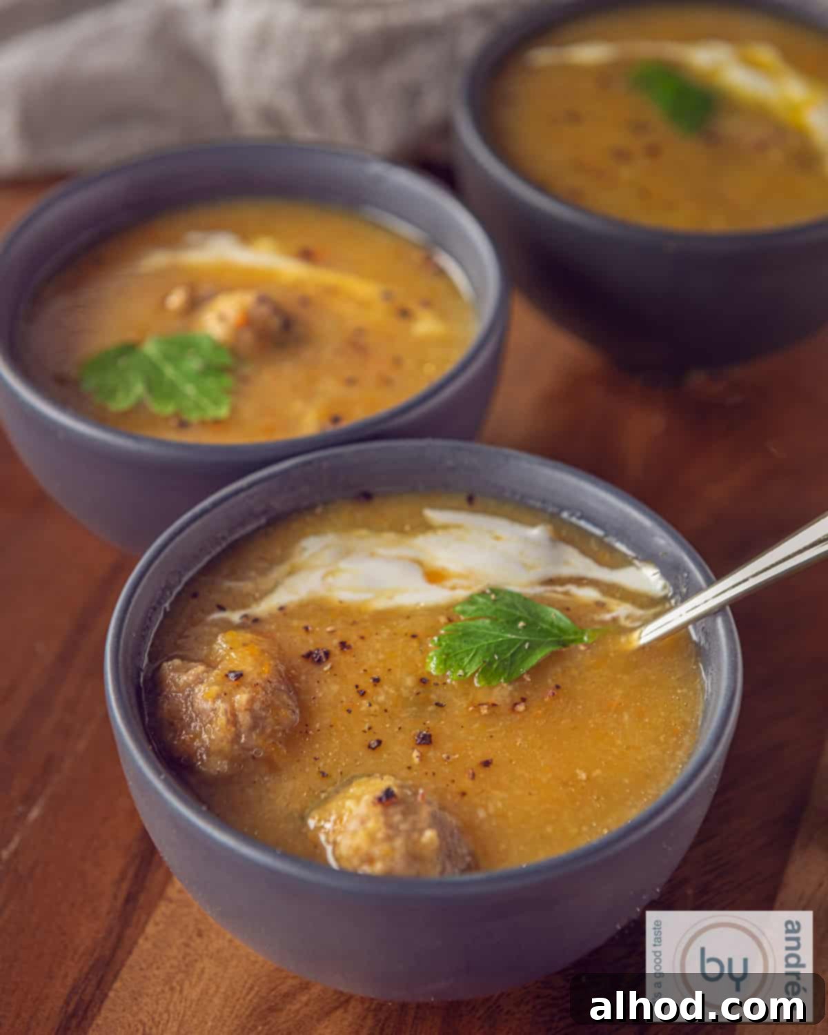 Cozy Creamy Slow Cooker Meatball and Vegetable Soup 3 An aerial photo with three bowls of soup with meatballs and vegetables and cream. A wooden plank as a base.