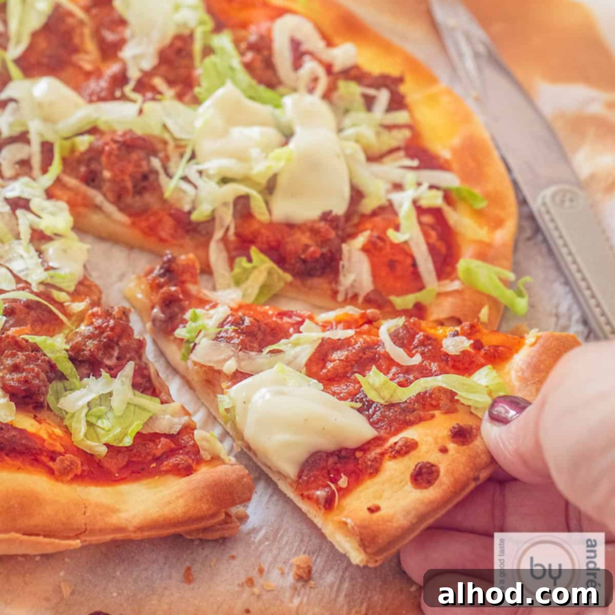 Lightning Fast Beef Taco Pizza with Zesty Garlic Drizzle 4 A square photo of a slice of pizza. A hand takes away a slice.