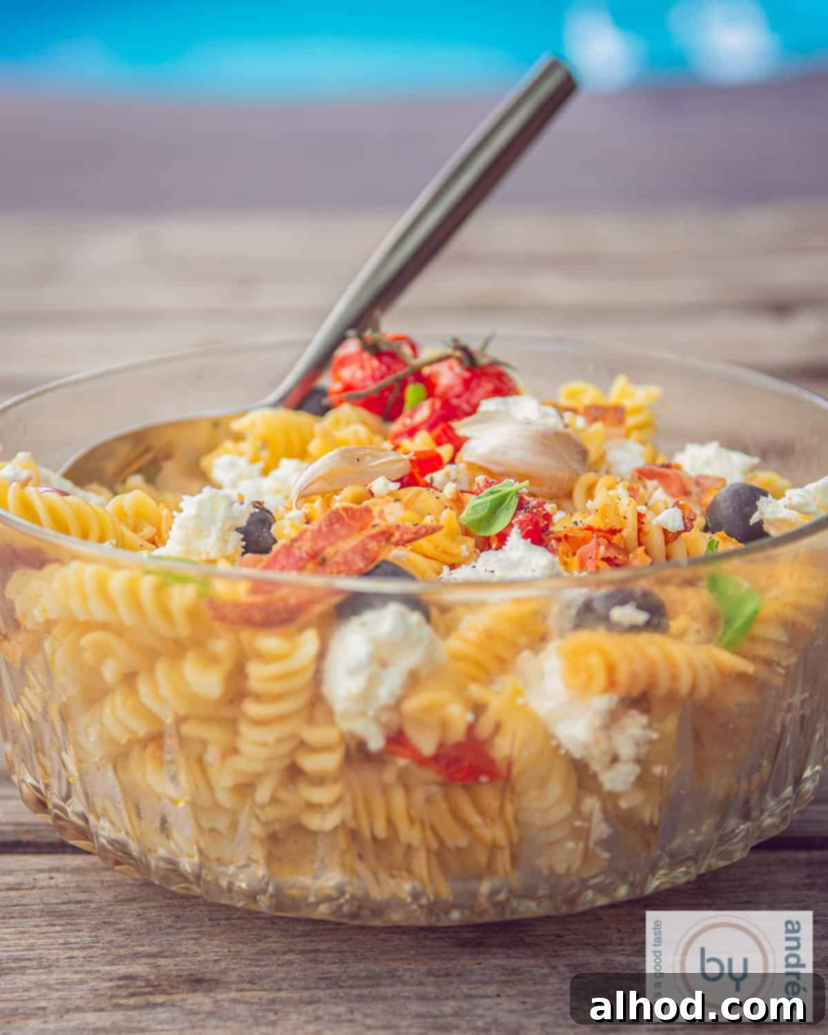 Mediterranean Bacon Feta Pasta Salad 2 A vibrant glass bowl filled with Tomato Feta Pasta Salad with Bacon, showcasing roasted tomatoes, crumbled feta, and fresh basil.