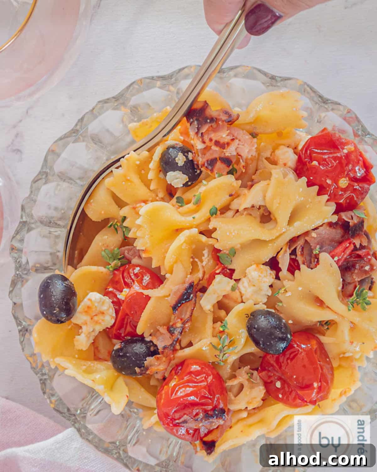 Mediterranean Bacon Feta Pasta Salad 3 An overhead shot showcasing the textures and colors of the pasta salad, with crumbled feta, crispy bacon bits, and roasted cherry tomatoes on a bed of pasta.
