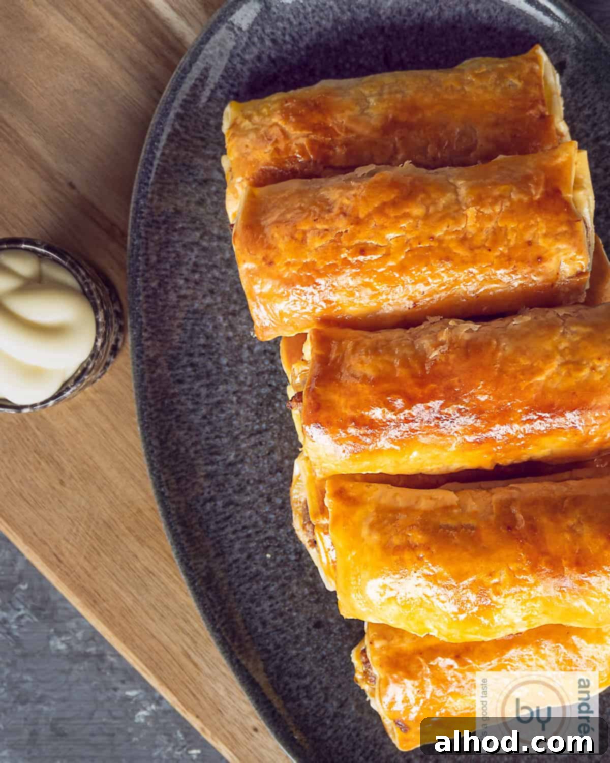 Flaky Dutch Sausage Rolls 3 Top view photo of a gray tray with a stack of sausage rolls and a bowl of mayo
