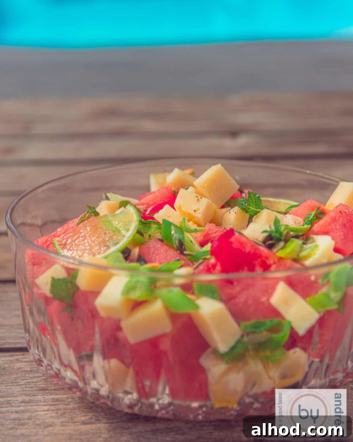 Vibrant Watermelon Mint Chevre Salad 3 A glass bowl with goat cheese cubes, watermelon, spring onion and lime. A refreshing summer salad ready to be served.