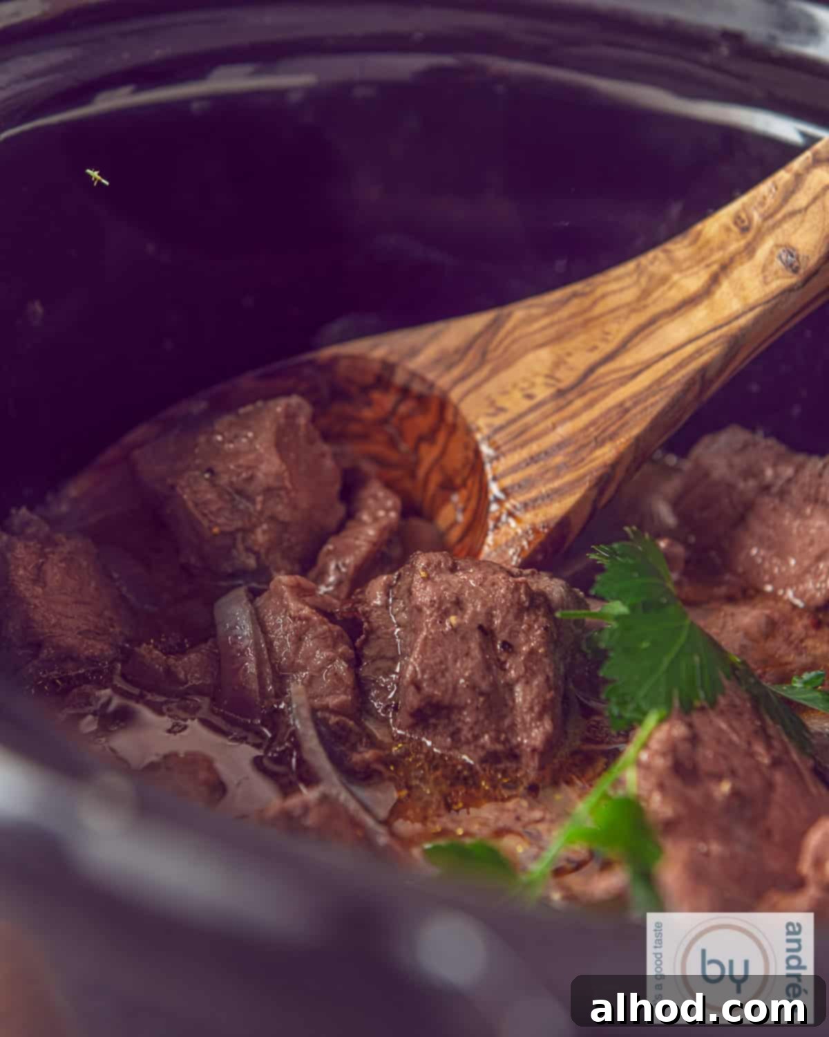 Part of a slow cooker with entrecote, onions and butter sauce.