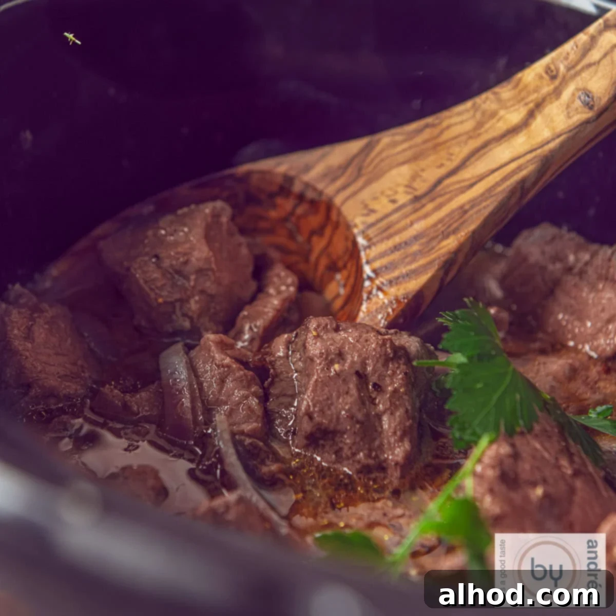 Garlic Infused Slow Cooker Steak Bites 4 A square photo showing part of a slow cooker containing entrecote with butter sauce.