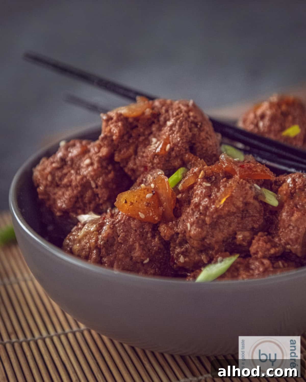 Indonesian Slow Cooker Meatballs in Savory Soy 3 A gray bowl with meatballs in ketjap sauce with two chopsticks