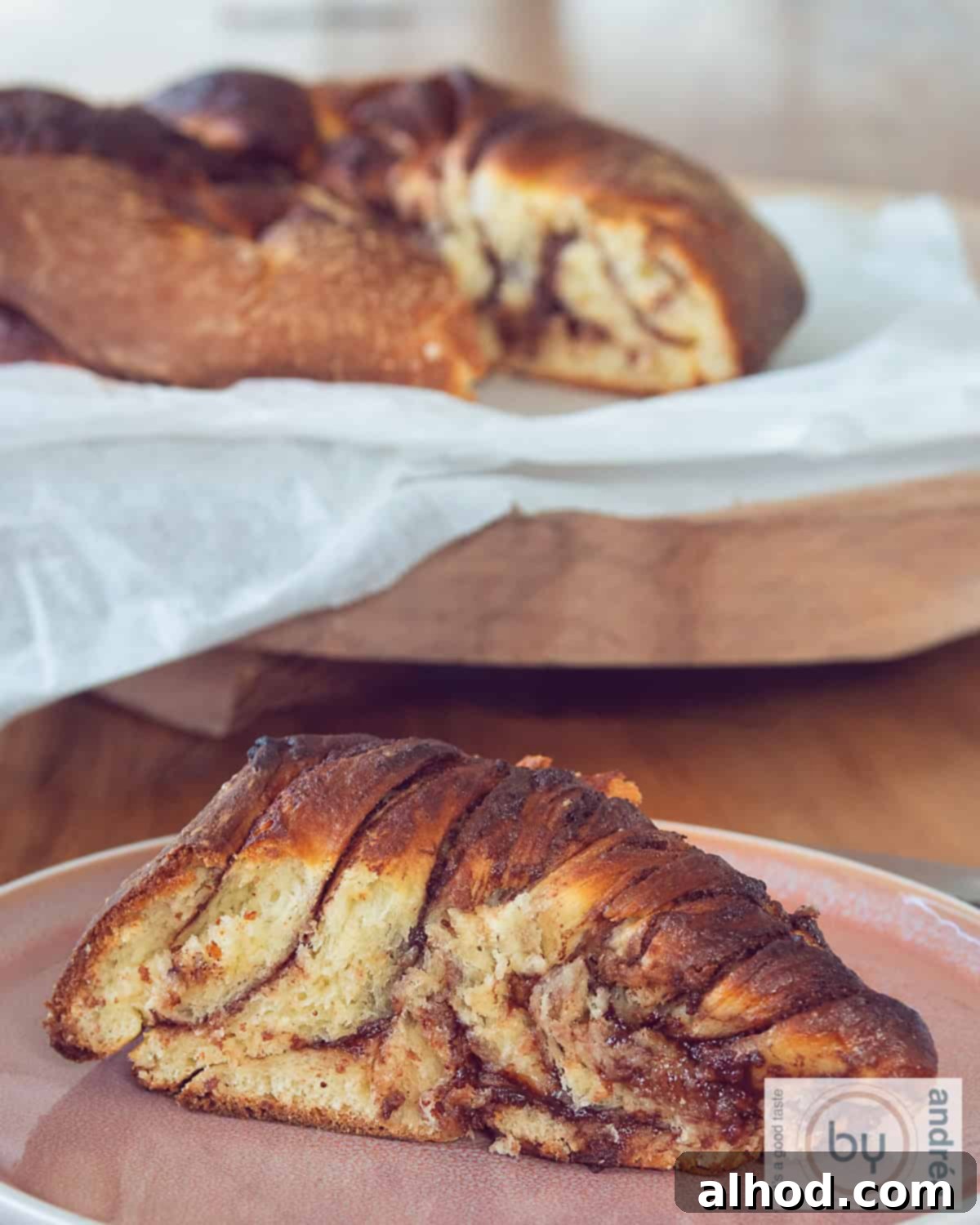 Chocolate Hazelnut Swirl Bread 2 A height picture of a part of Nutella twist bread on a pink plate. A loaf of bread in the background.