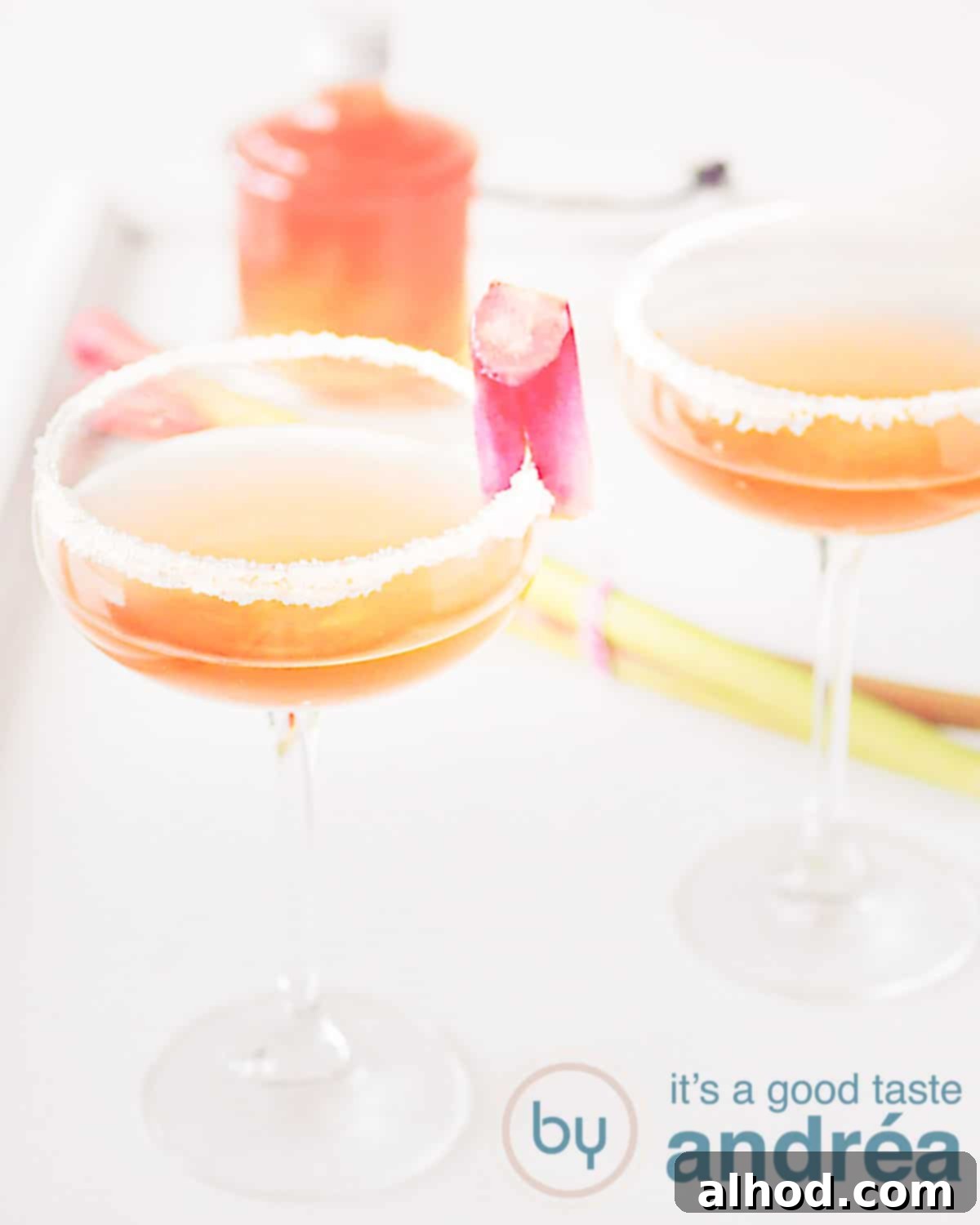 Rhubarb Champagne Sparkler 2 two glasses Rhubarb champagne cocktail with rhubarb syrup in the background
