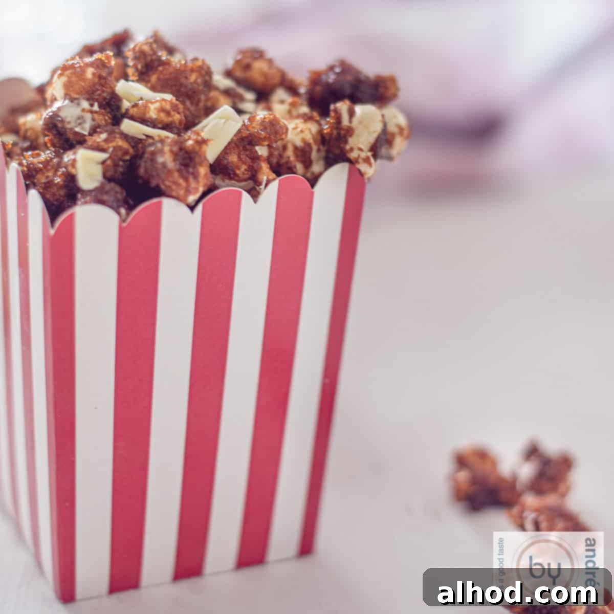 Gourmet White Chocolate Caramel Popcorn 4 A red and white striped container filled with homemade white chocolate caramel popcorn