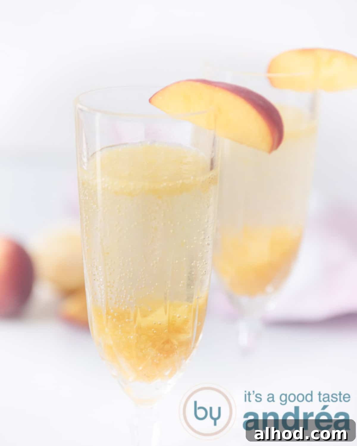 Peach Bellini 5 Two glasses filled with Italian Bellini drink with peach. Two peaches in the background with a white background