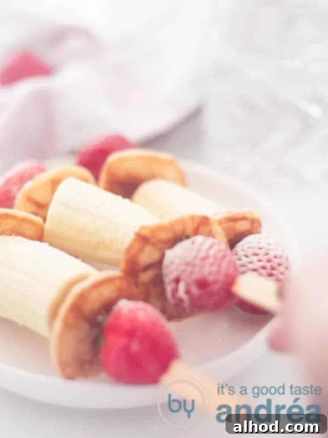 Strawberry Banana Pancake Pops 5 3 banana strawberry poffertjes treat on a white plate. A hand takes one away.