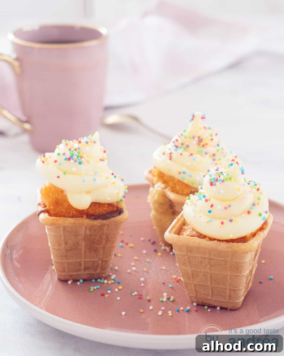 Fun Ice Cream Cone Cupcakes 3 A charming pink plate showcasing three perfectly frosted ice cream cone cupcakes, adorned with colorful disco dip sprinkles.