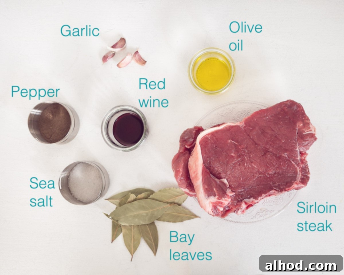 Madeira Style Beef Skewers 3 Ingredients for Portuguese Beef Skewers (Espetada Madeira) laid out on a white background, including sirloin steak, garlic, red wine, bay leaves, olive oil, and sea salt.