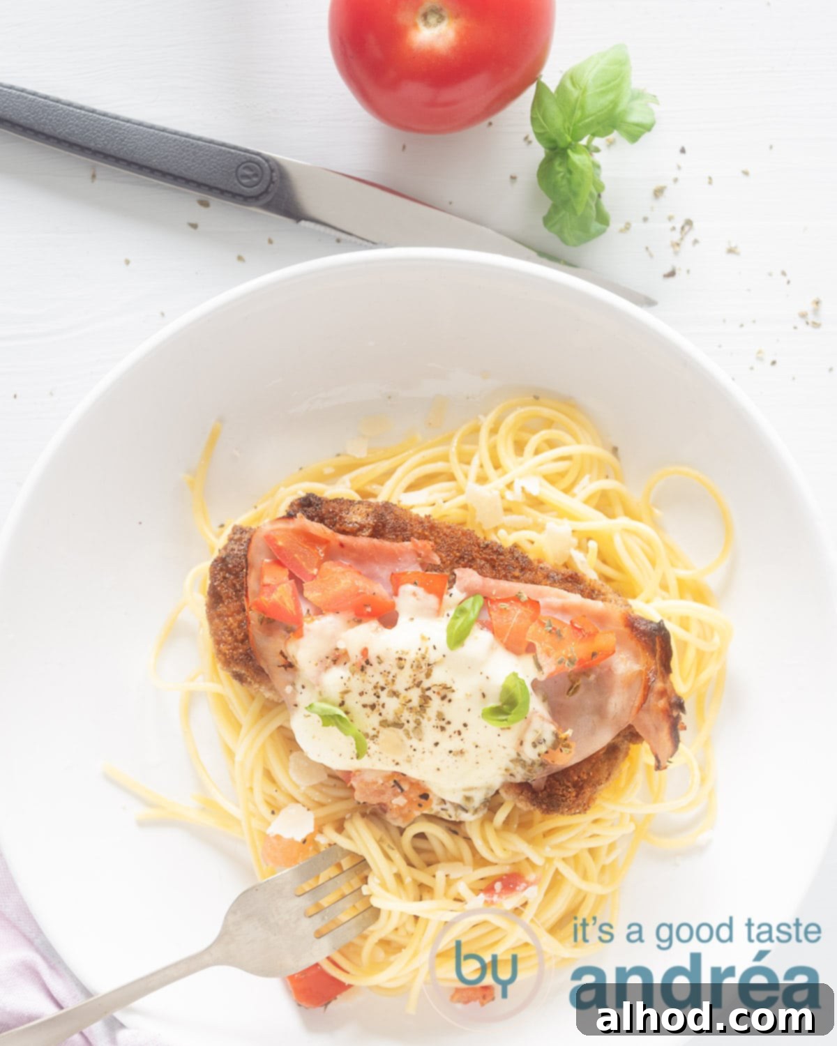 Argentine Milanesa Napolitana: A Crispy, Cheesy Steak Sensation 2 A photo from above. A white plate of spaghetti and topped with an Argentinian Italian-style schnitzel with Mozzarella, ham and tomato