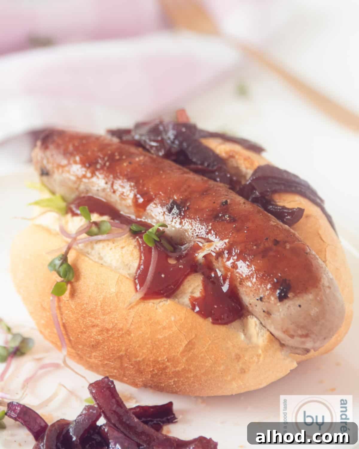 Grilled Beer Brats Crowned with Sweet Caramelized Onions 2 Bratwurst on a bun with onion and curry garnish