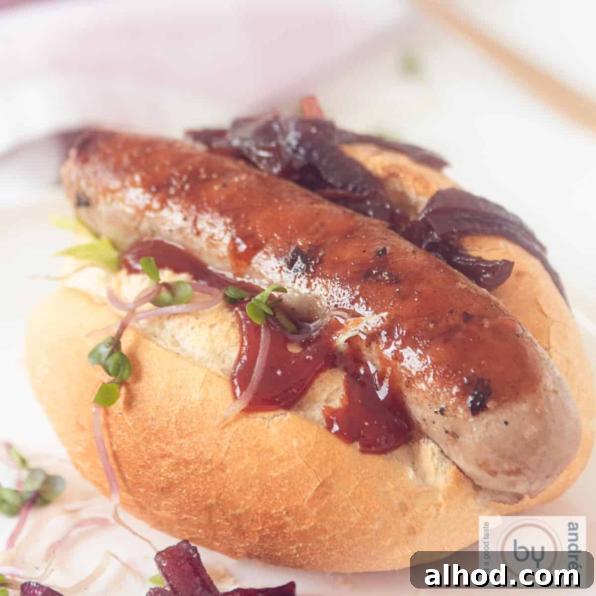 Grilled Beer Brats Crowned with Sweet Caramelized Onions 4 A square photo with a sandwich filled with grilled sausage and sweet caramelized onions