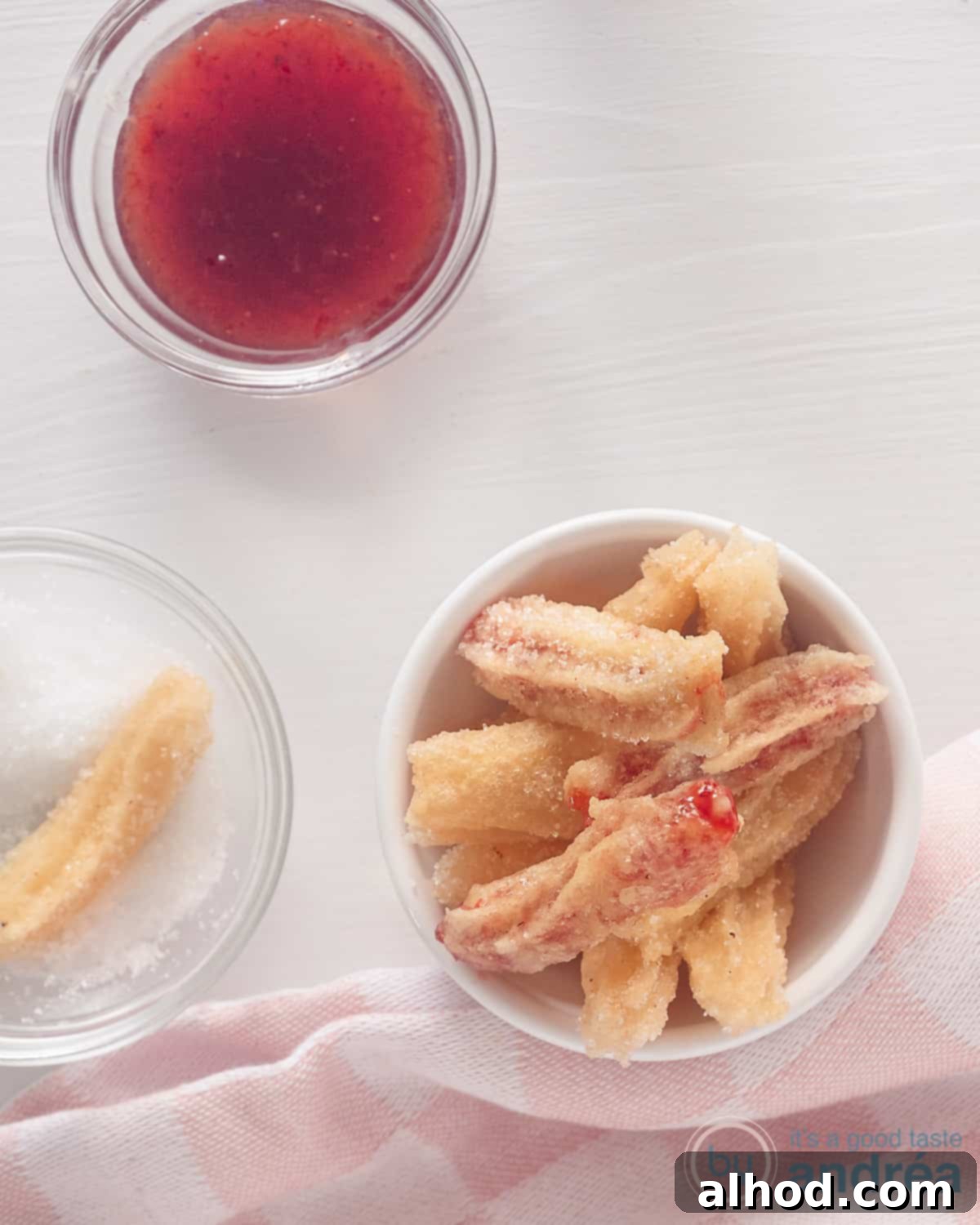 Strawberry Burst Churros 2 A photo from above of three bowls. The white bowl is filled with strawberry churros, a second with sugar with a churro and the third bowl with strawberry jam.