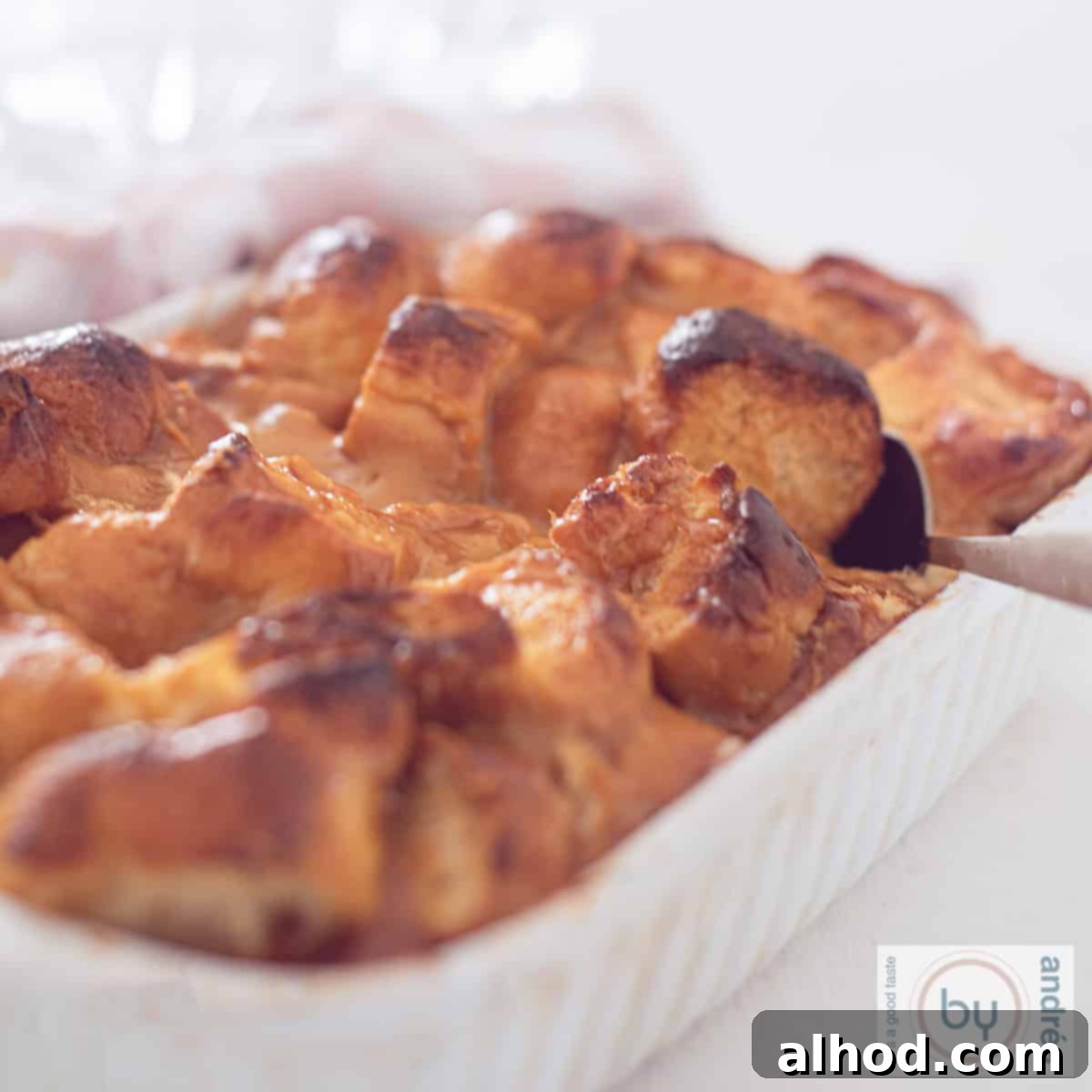 Decadent Dulce de Leche Bread Pudding 4 A square photo with a bread pudding with Dulce de Leche and brioche. A spoon takes a scoop