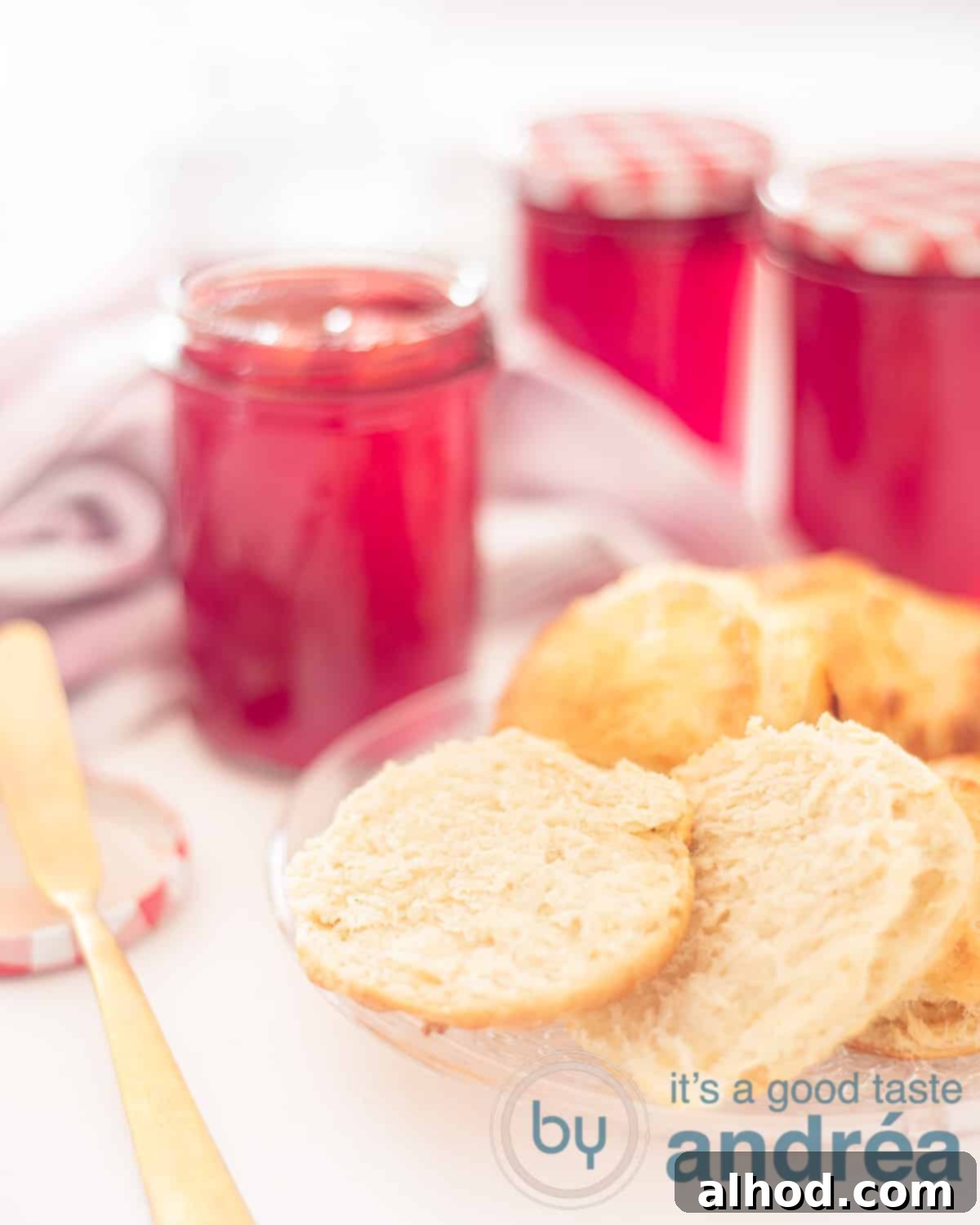 Sweet Strawberry Scones Made Easy 2 An elevation photo on the right a glass plate with scones, 1 cut in half showing two sides. In the background three jars of jam, one of which is open.
