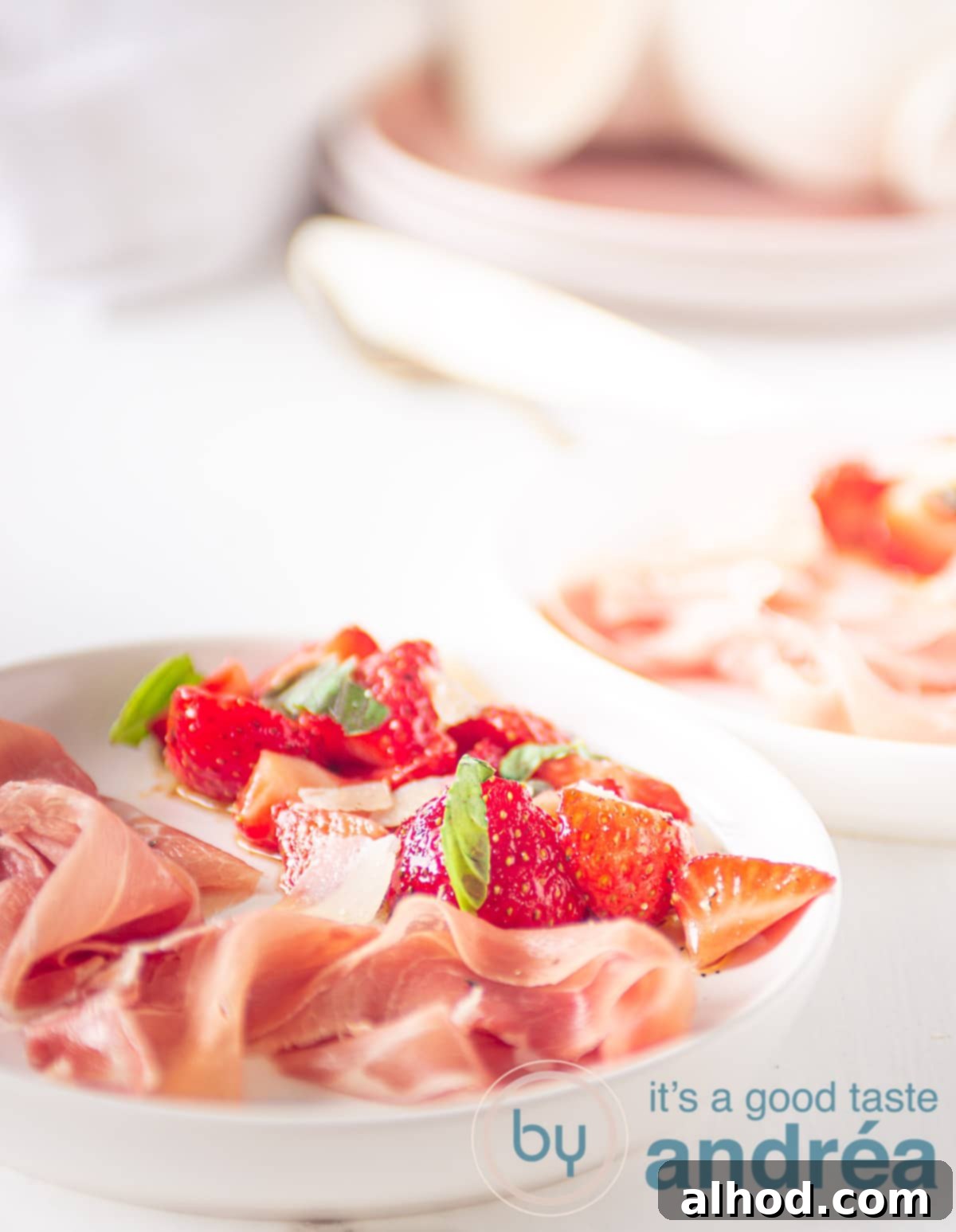Balsamic Basil Strawberry Bliss 5 Marinated strawberries and Parmaham on a white plate with plates in the background