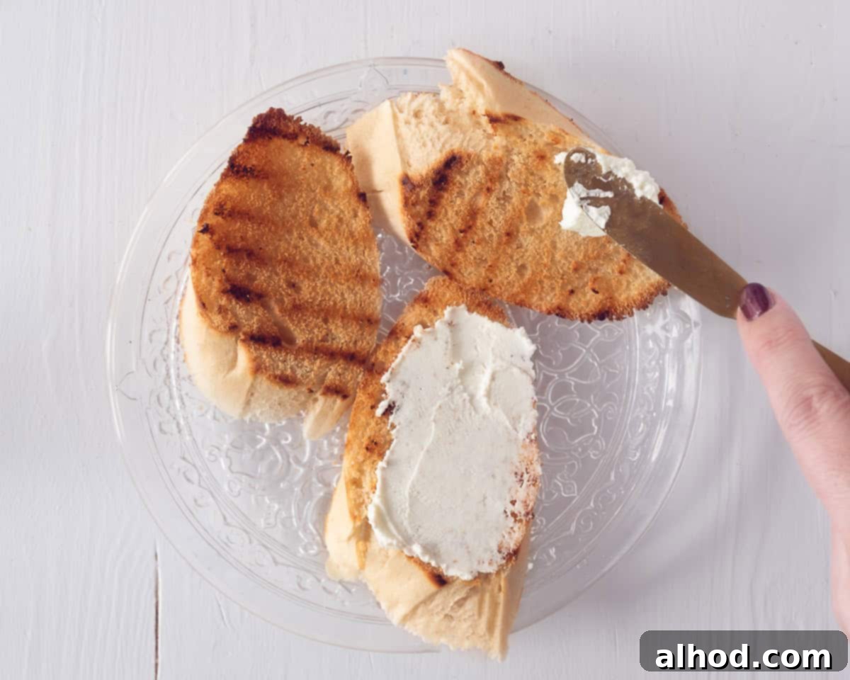 a glass plate on a white background. Grilled baguette slices where mascarpone is smeared on top