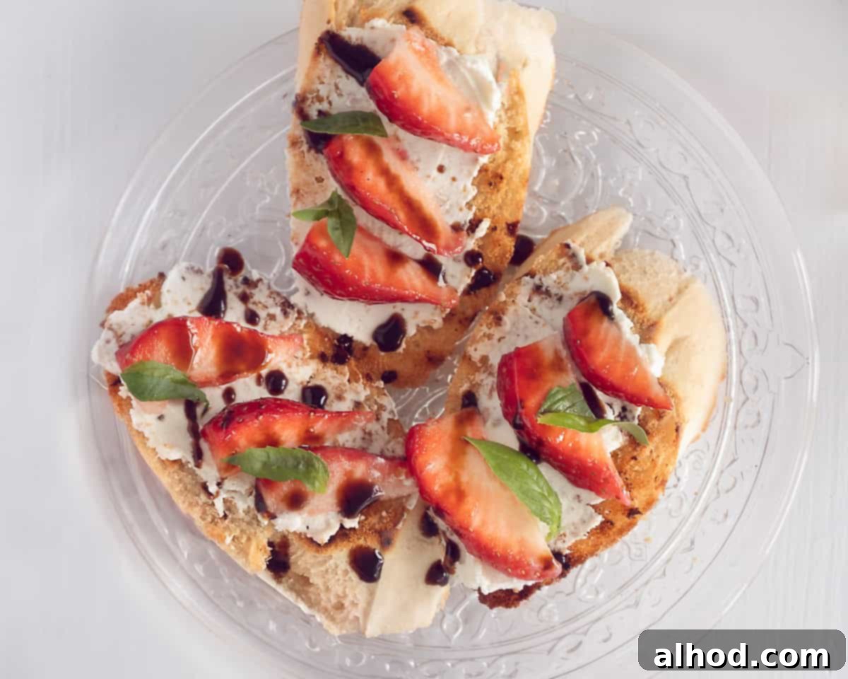 Strawberry Balsamic Bruschetta 7 Three slices of baguette topped with mascarpone, strawberries, balsamic glaze, and strips of fresh basil, creating a visually appealing and delicious appetizer.