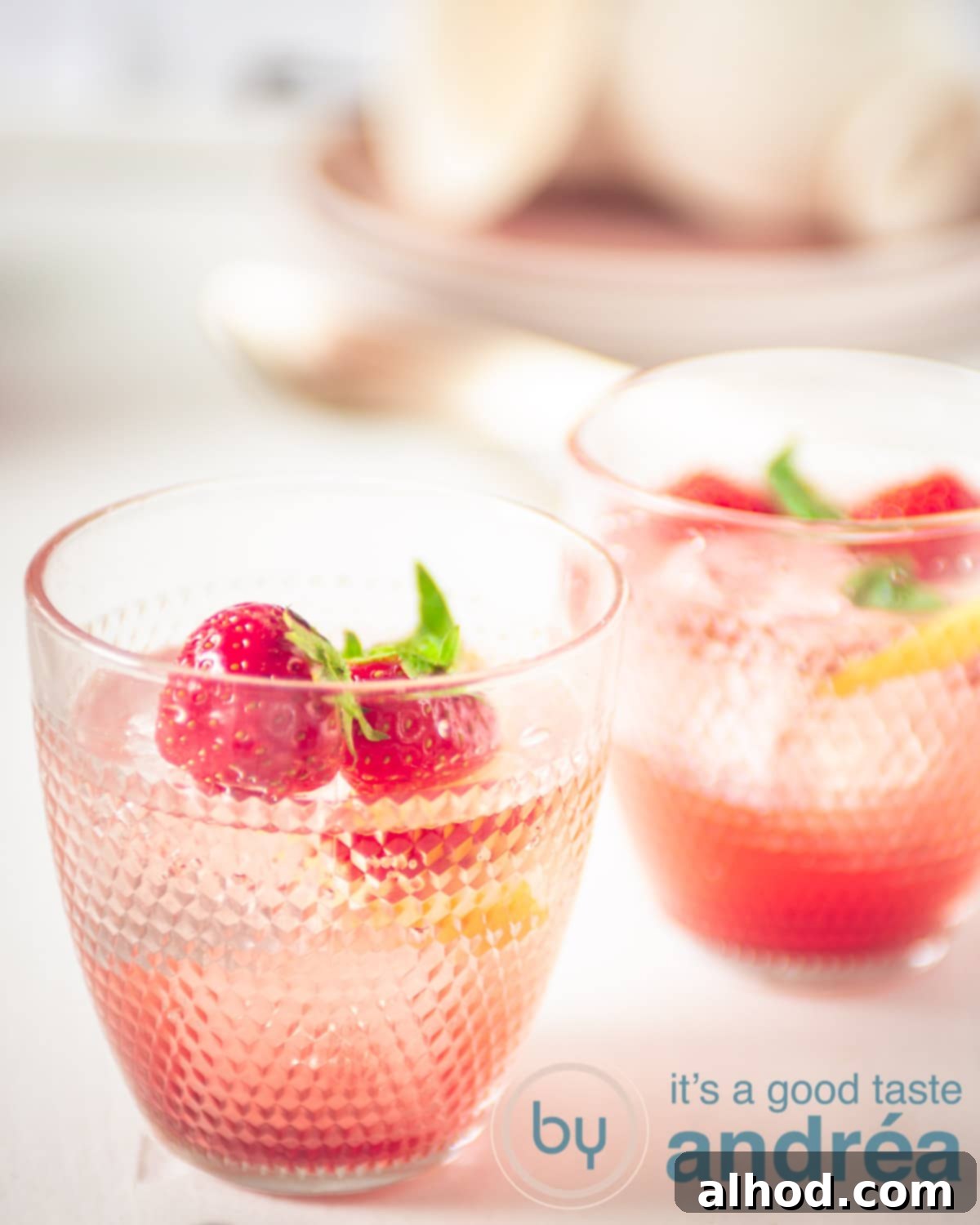 Strawberry Lemonade Mocktail with Basil 5 Two elegant glasses of homemade strawberry basil lemonade mocktail, garnished with fresh strawberry slices and lemon wedges.