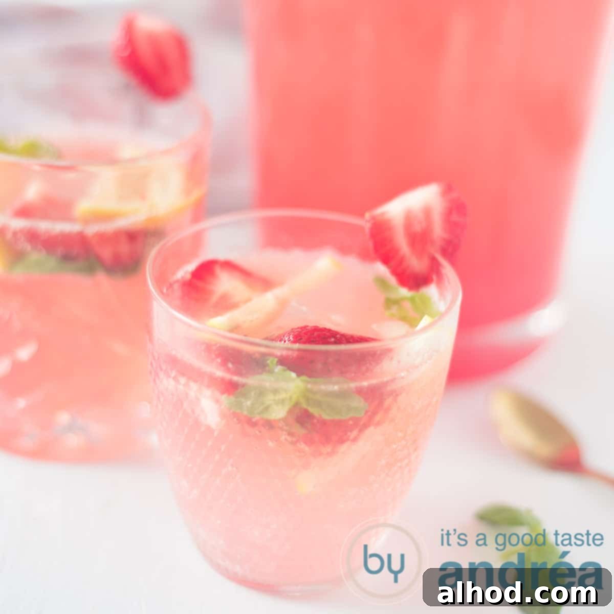 Strawberry Lemonade Mocktail with Basil 6 A square photo with two glasses filled with strawberry basil lemonade mocktail with fresh fruit and a pitcher in the background.