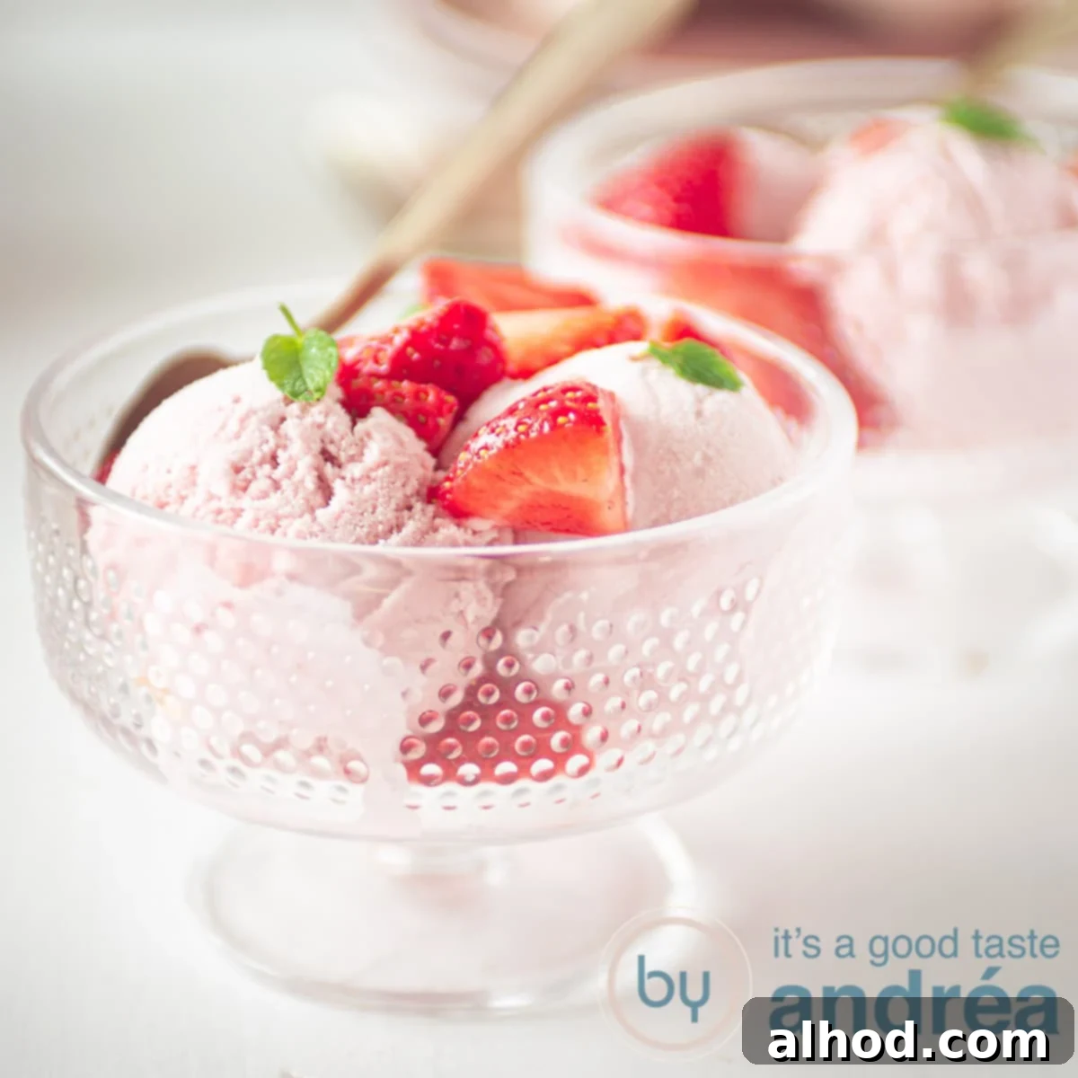 Easy No Churn Strawberry Ice Cream 6 A square photo with two glass bowls filled with strawberry ice cream balls, fresh strawberries and mint.