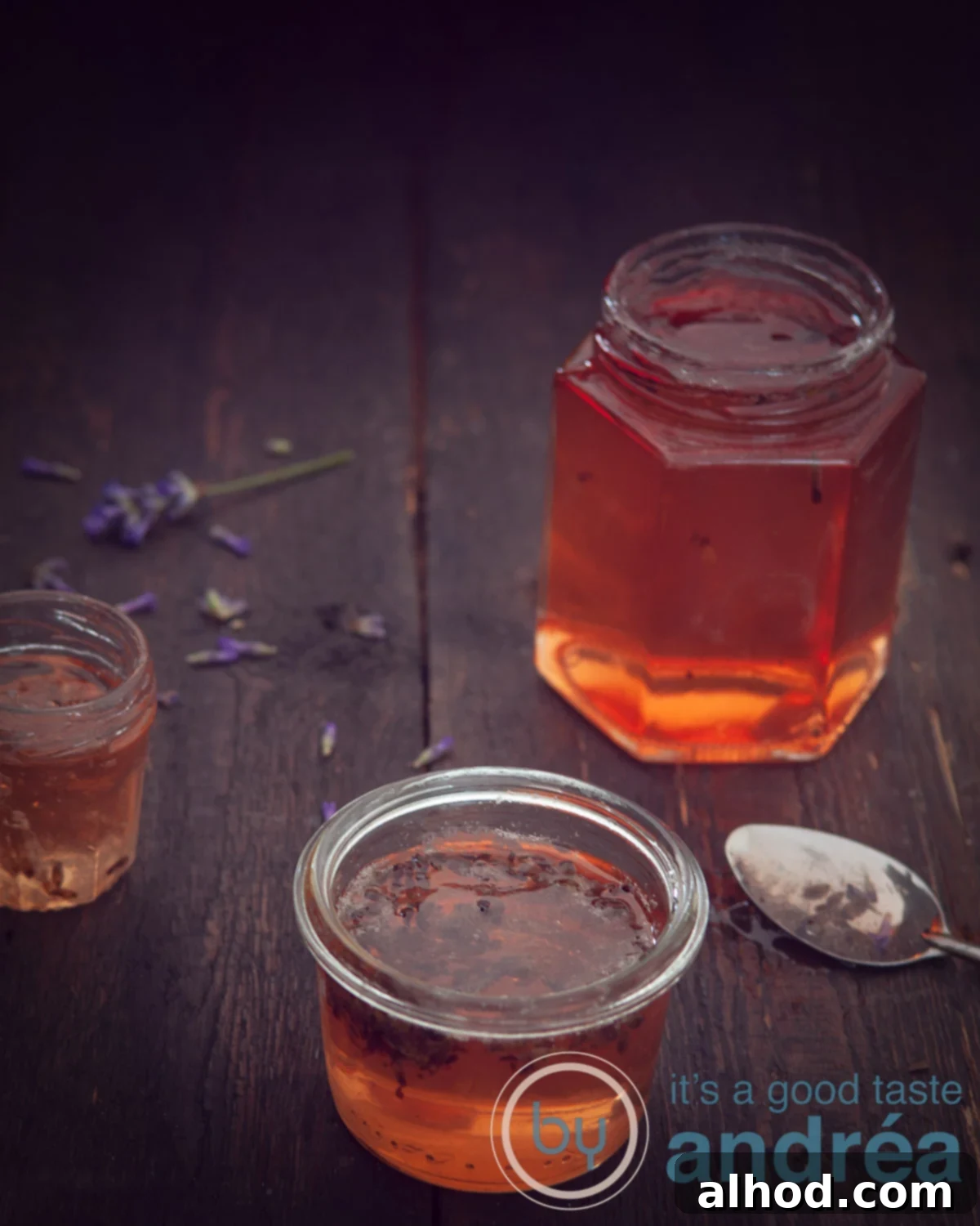 Lavender Kissed Apple Jelly 8 Three jars of golden apple jelly with a hint of lavender, glistening on a dark background, perfectly set and ready to be enjoyed.