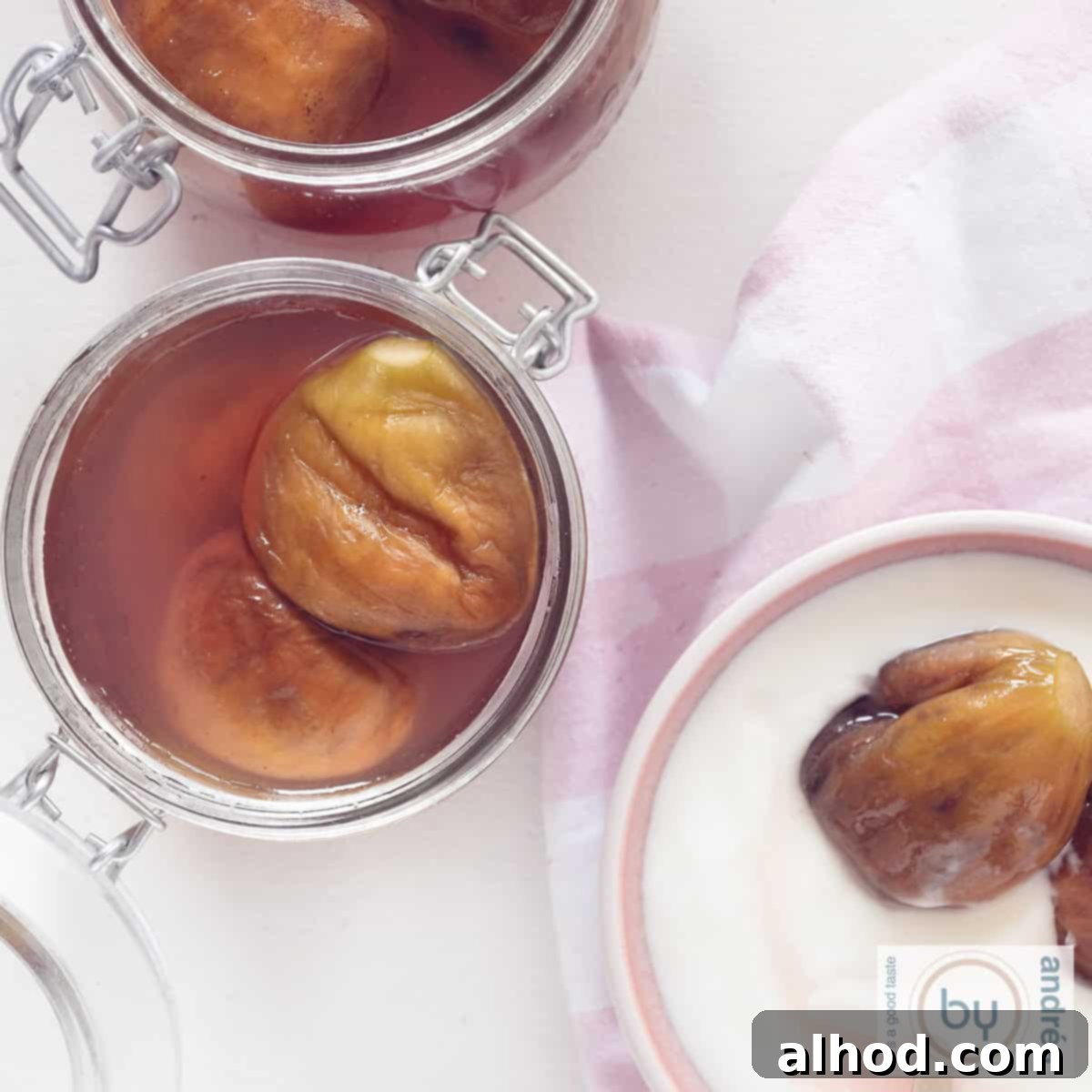 The Art of Syruped Figs: Preserving Sweetness 4 A square photo showing two glass jars brimming with preserved figs in syrup on the left, and a pink bowl containing yogurt topped with figs on the bottom right. The image captures the rich texture and appealing presentation of the sweet treat.