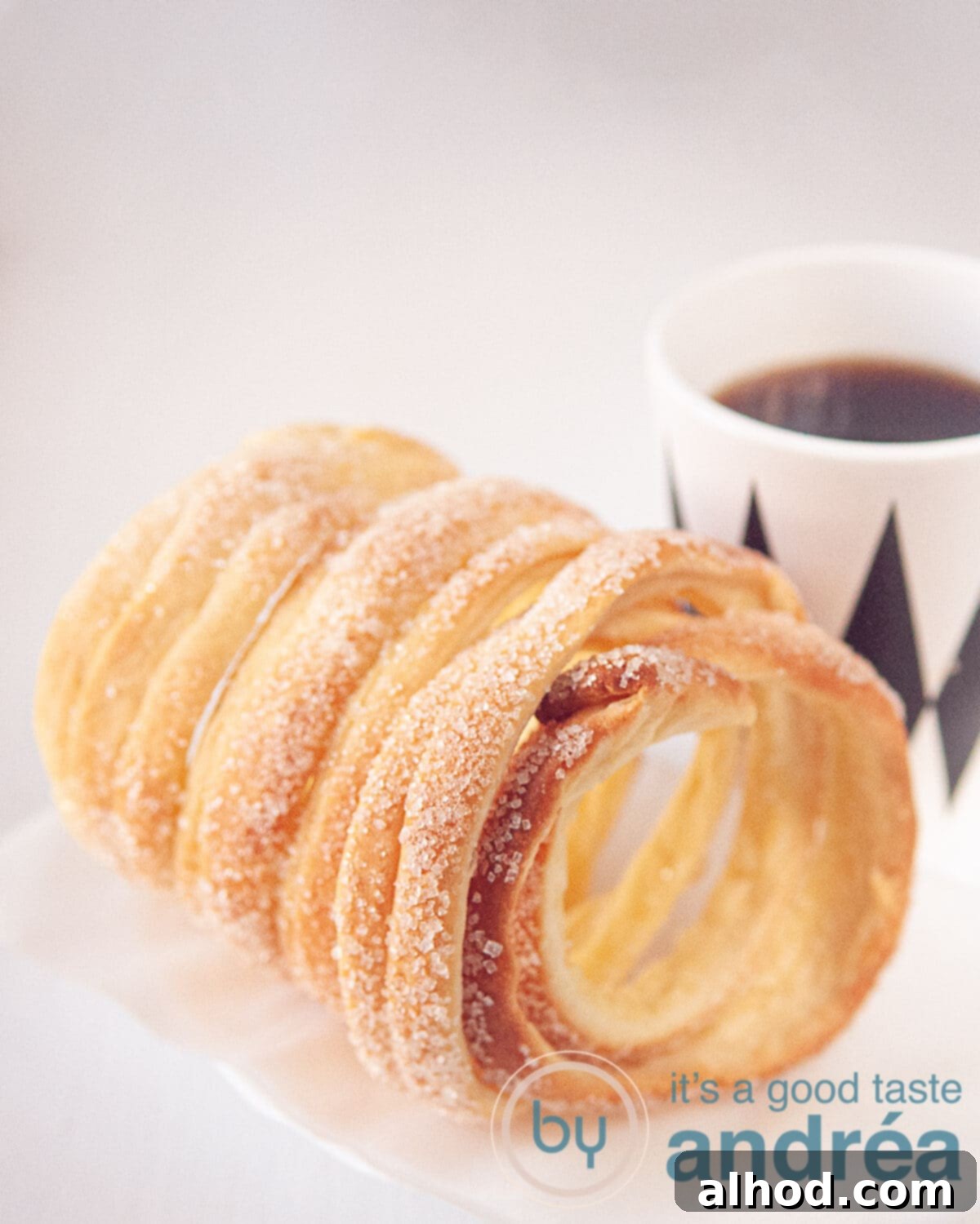 A chimney cake with a cup of coffee (in a white with black mug)