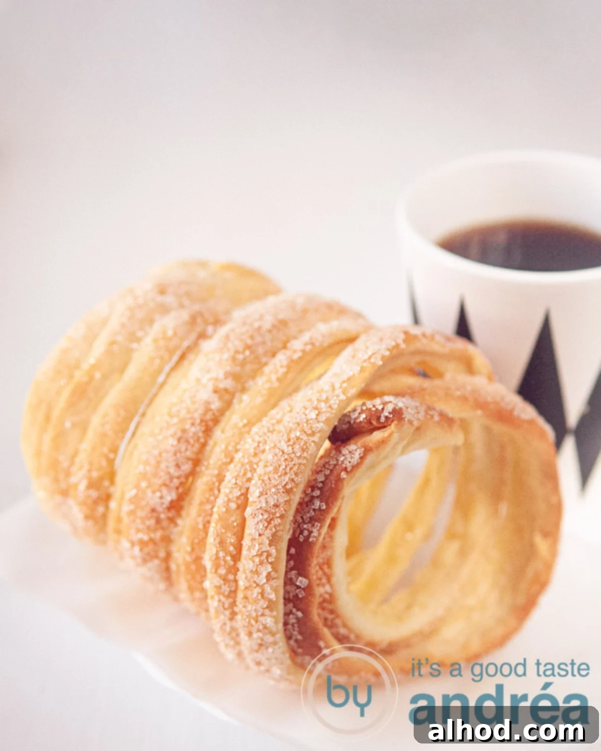 A chimney cake with a cup of coffee (in a white with black mug)