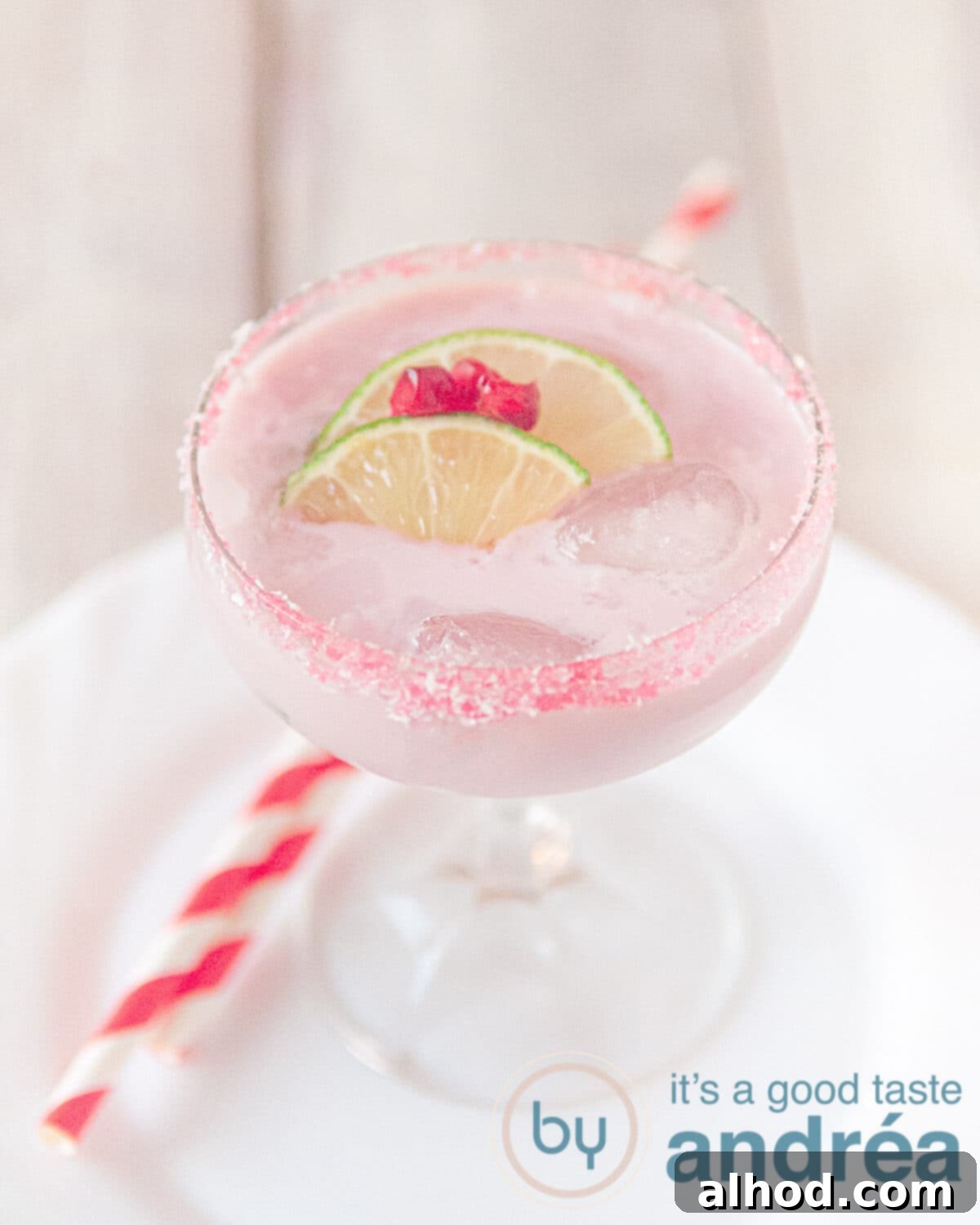 A vibrant fresh pomegranate cocktail, elegantly garnished with a wedge of lime and fresh pomegranate arils, highlighting its rich color.