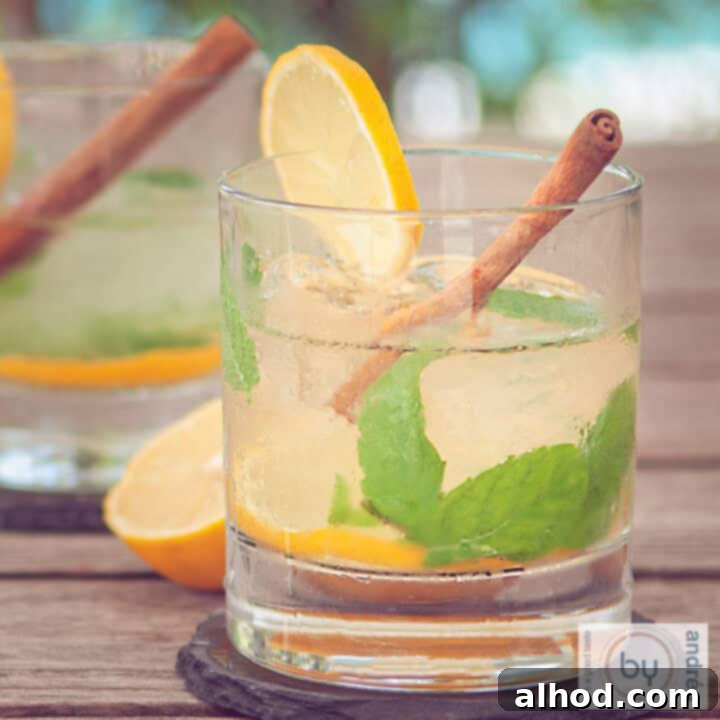 A square picture showcasing two glasses filled with a vibrant ginger caipirinha, garnished with fresh mint leaves, lemon slices, and a cinnamon stick, creating an inviting spice and citrus blend.