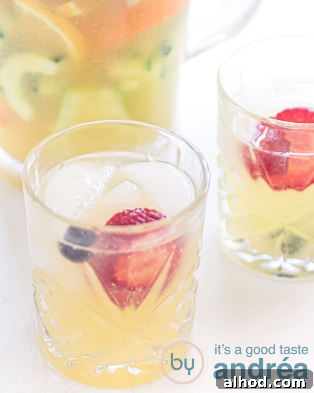 A tall glass filled with Virgin Pimm's mocktail, garnished with fresh mint, cucumber slices, and various berries, on a vibrant summer background.