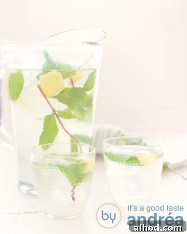 A clear glass and a large pitcher filled with homemade ginger iced tea, garnished with fresh mint sprigs and ginger slices, against a clean white background.