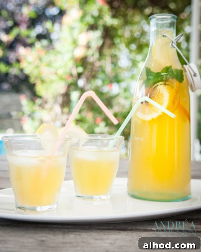 A large pitcher of homemade orange iced tea, garnished with citrus slices, and two glasses ready to be poured, capturing a bright, refreshing vibe.