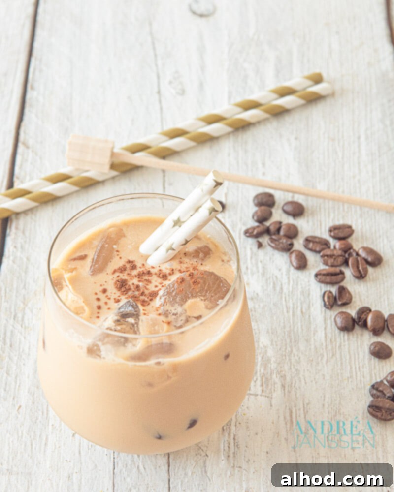 A tall, elegant glass of creamy iced coffee, garnished with coffee beans, emphasizing its refreshing and luxurious qualities, on a clean white surface.