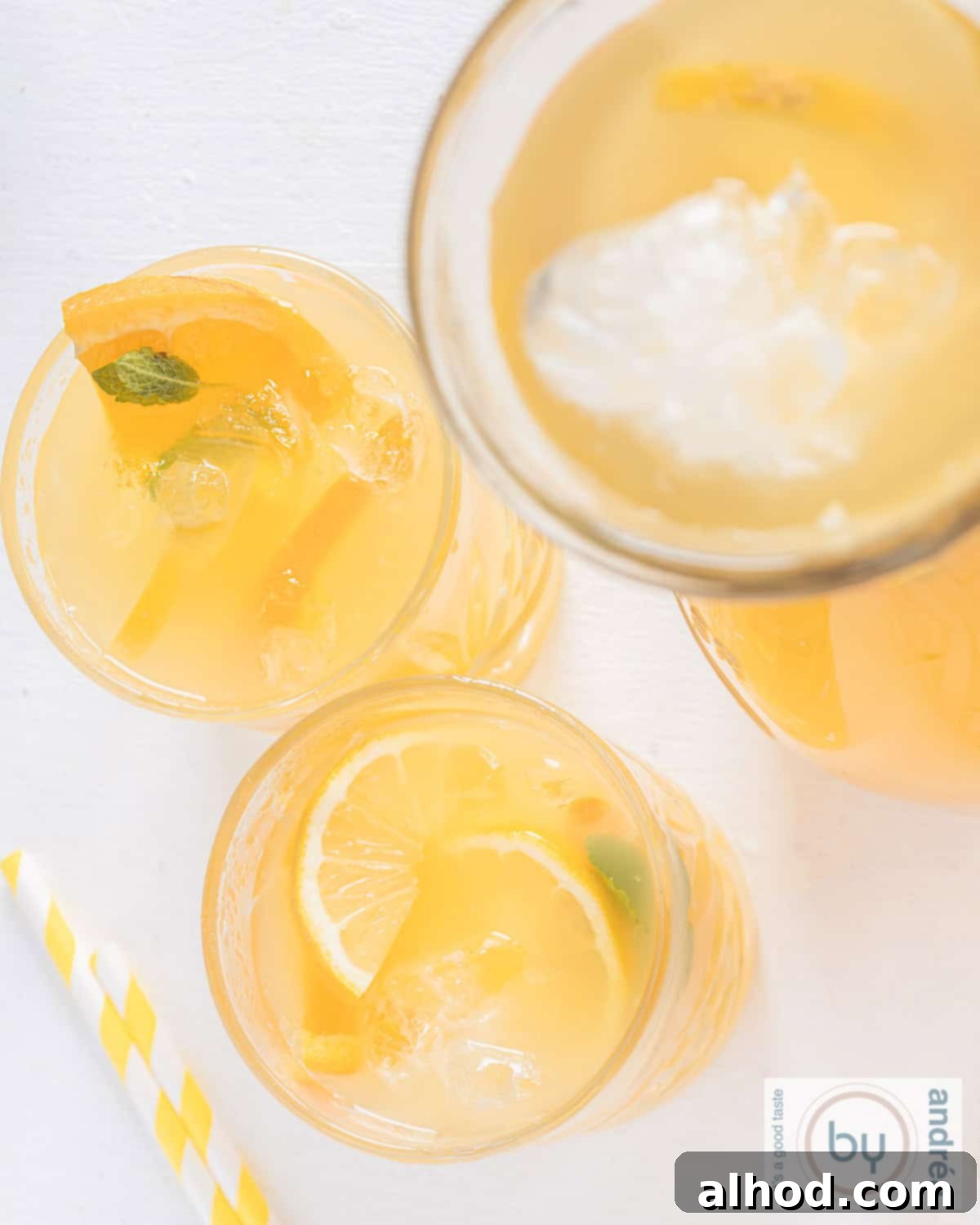 Lemon Mint Cooler 3 An overhead shot showcasing two glasses and a clear carafe filled with vibrant lemon and mint iced tea, adorned with fresh citrus slices and mint sprigs.