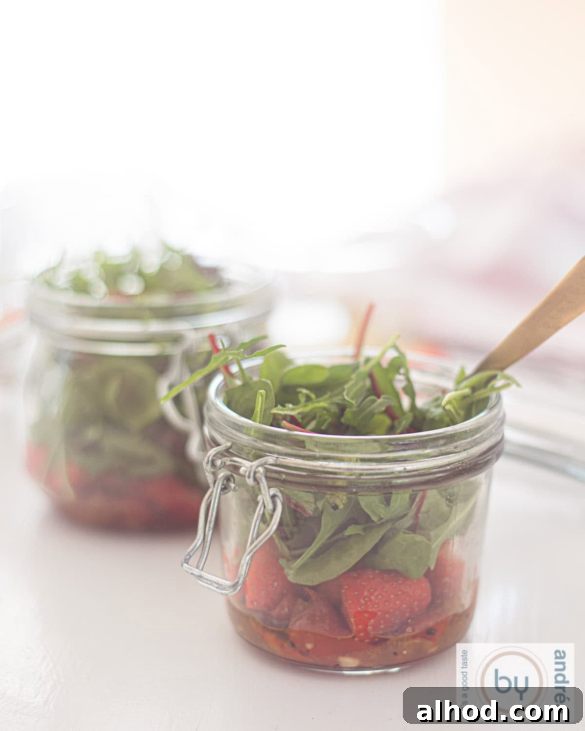 Layered Summer Salad Creations 2 Two jars with a green salad, sun-dried tomatoes, strawberries, and a honey mustard dressing