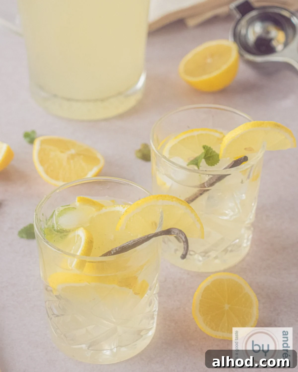 Two glasses filled with homemade vanilla lemonade, adorned with lemon slices and a vanilla pod, captured from a height.