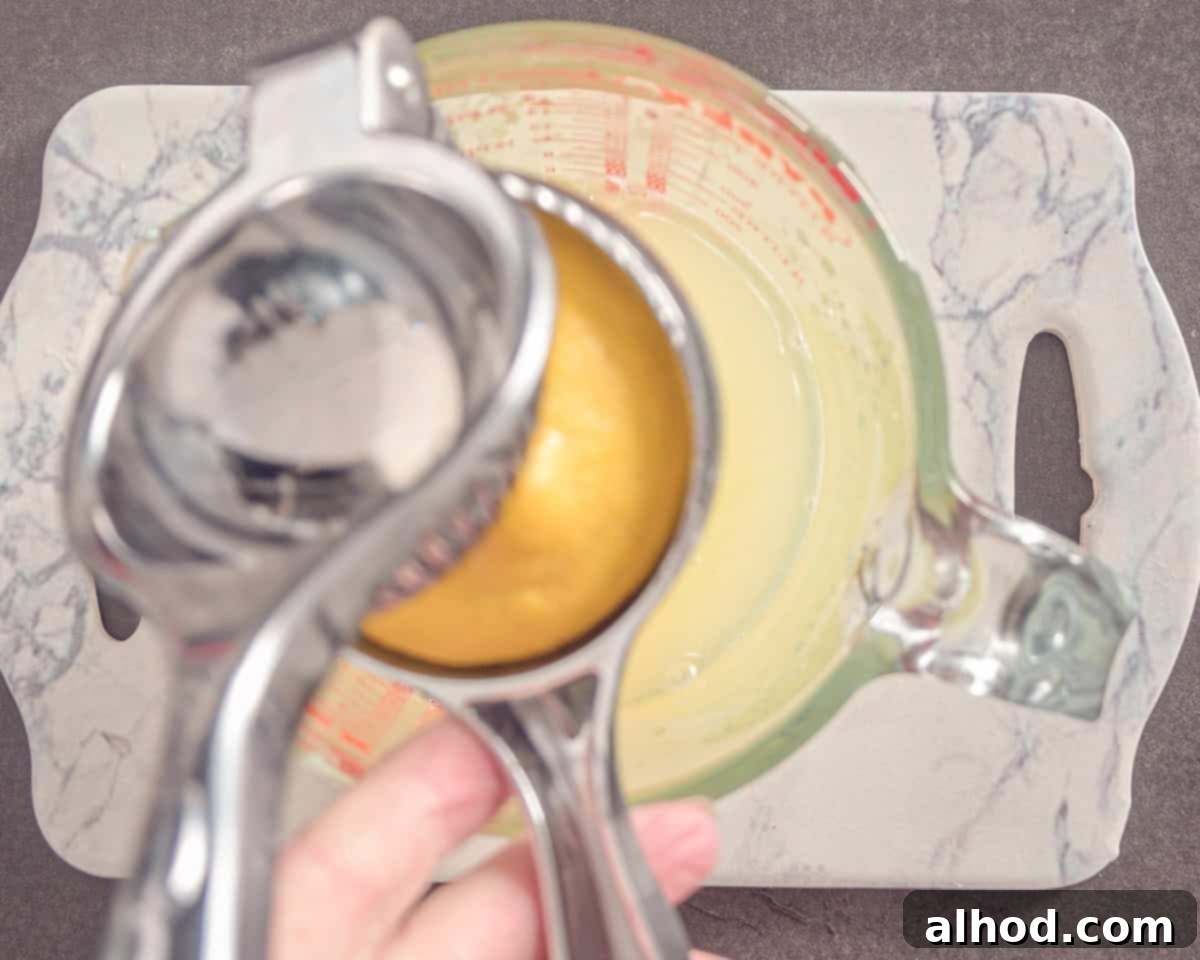 Hands squeezing lemon halves over a reamer to extract fresh lemon juice.