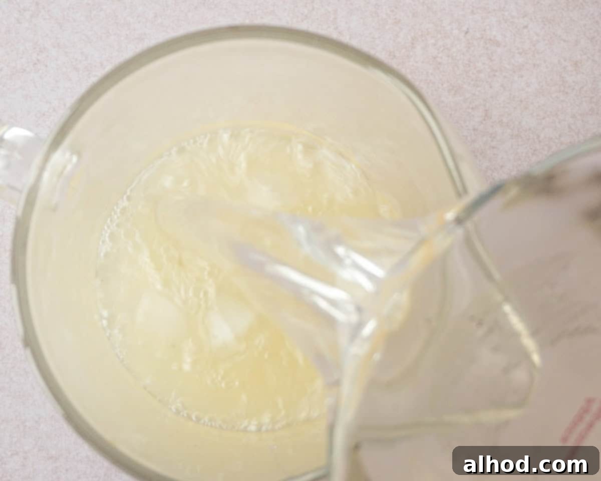 Pouring the cooled vanilla sugar syrup into a jug containing fresh lemon juice.