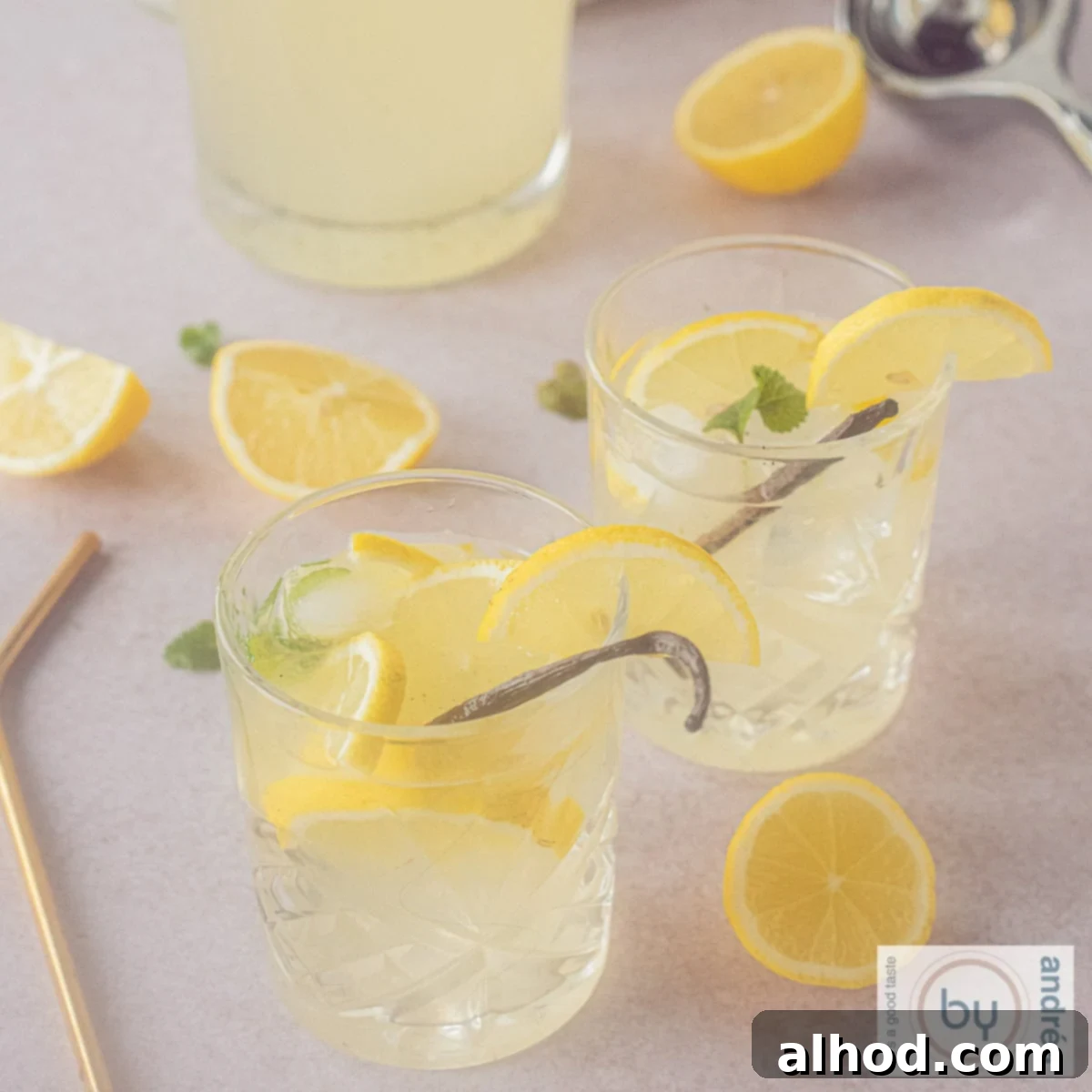 Two glasses of homemade vanilla lemonade garnished with lemon slices and fresh mint, perfect for a refreshing summer drink.